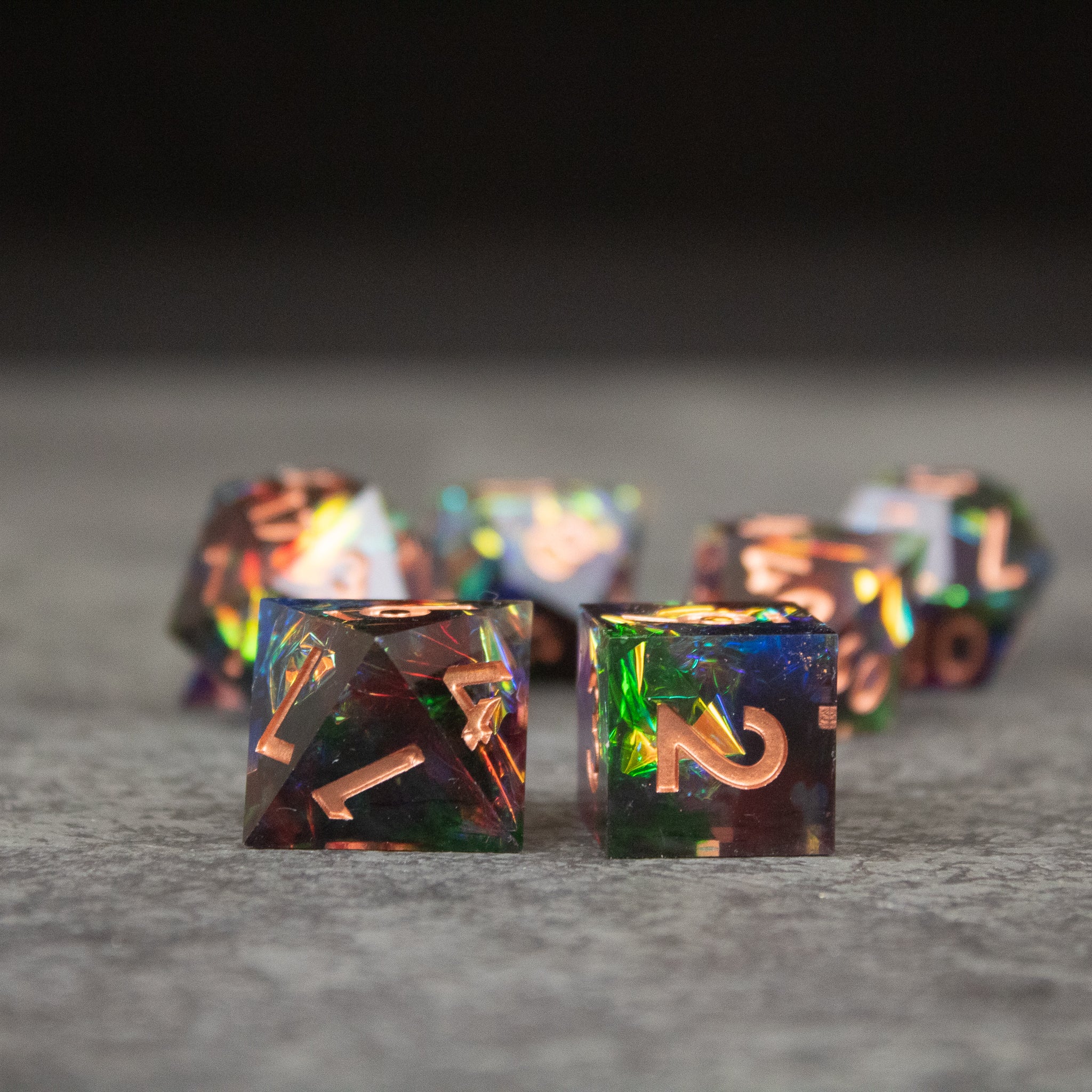 Aurora Dice Set - Set of sharp-edged rainbow dice with iridescent colors and gold numbering on translucent faces.