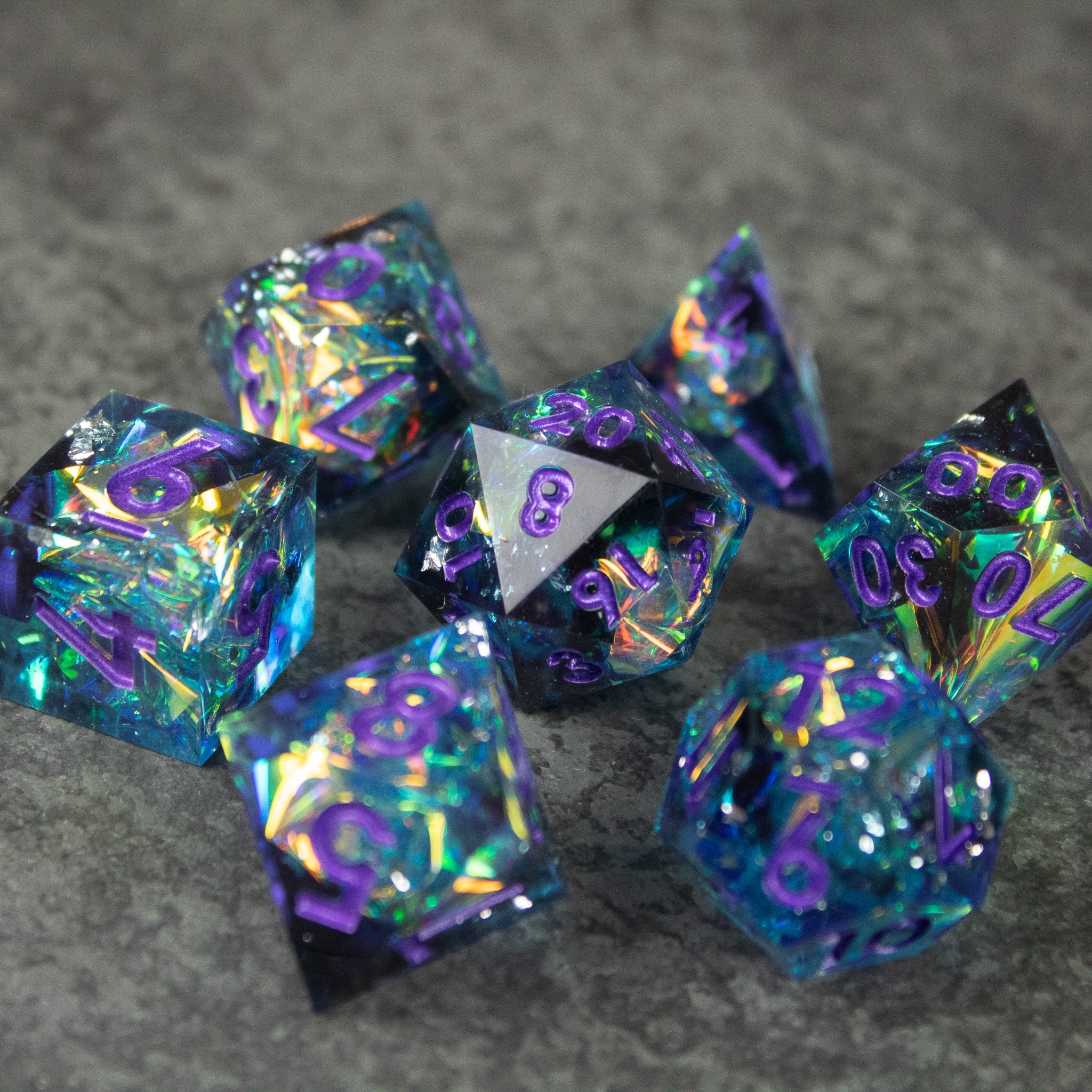 Frostbite Dice Set - Black and blue sharp-edged polyhedral dice set with iridescent shimmer and purple numbering.