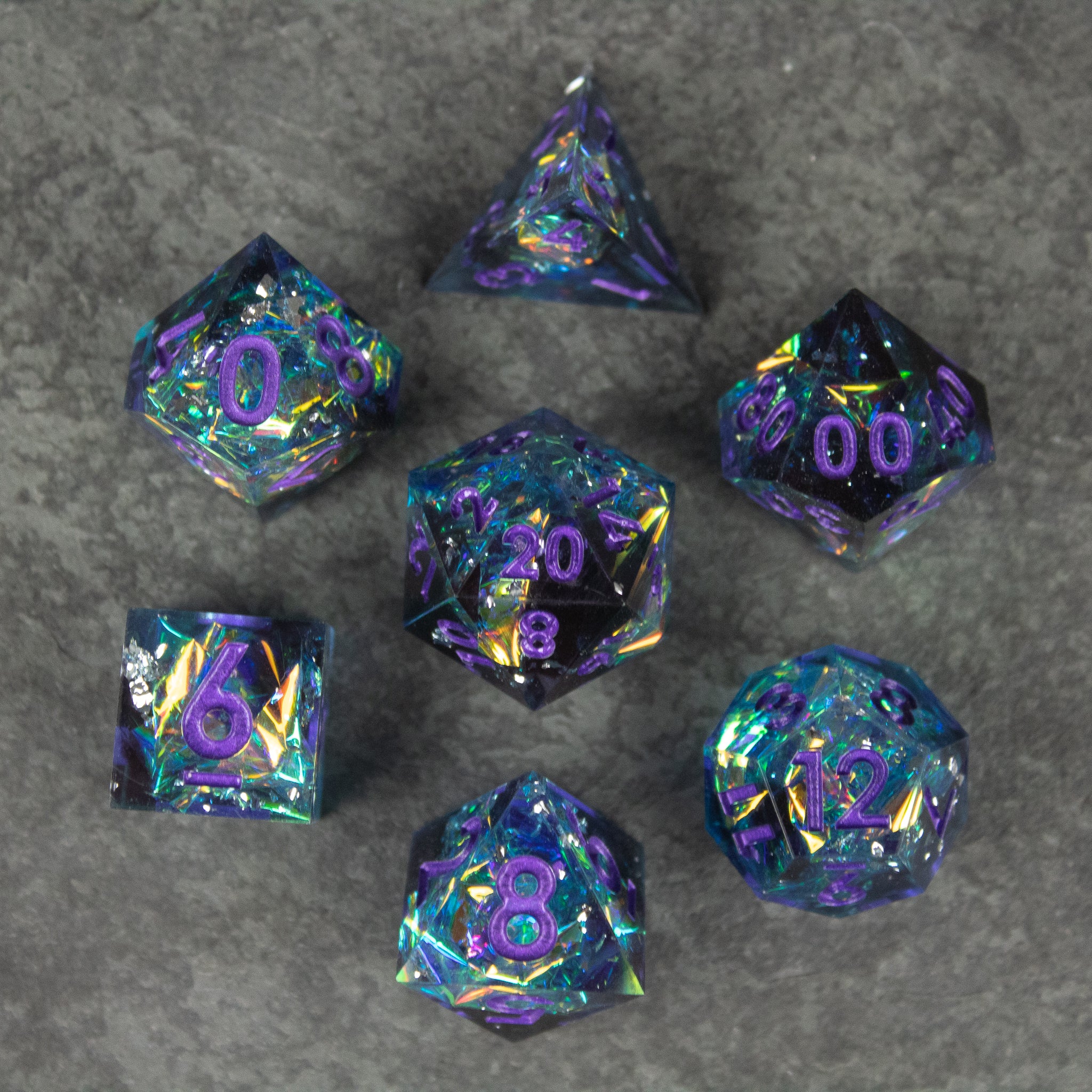 Frostbite Dice Set - Seven polyhedral dice in black with sharp edges, featuring iridescent blue, purple, and green swirls and bright purple.