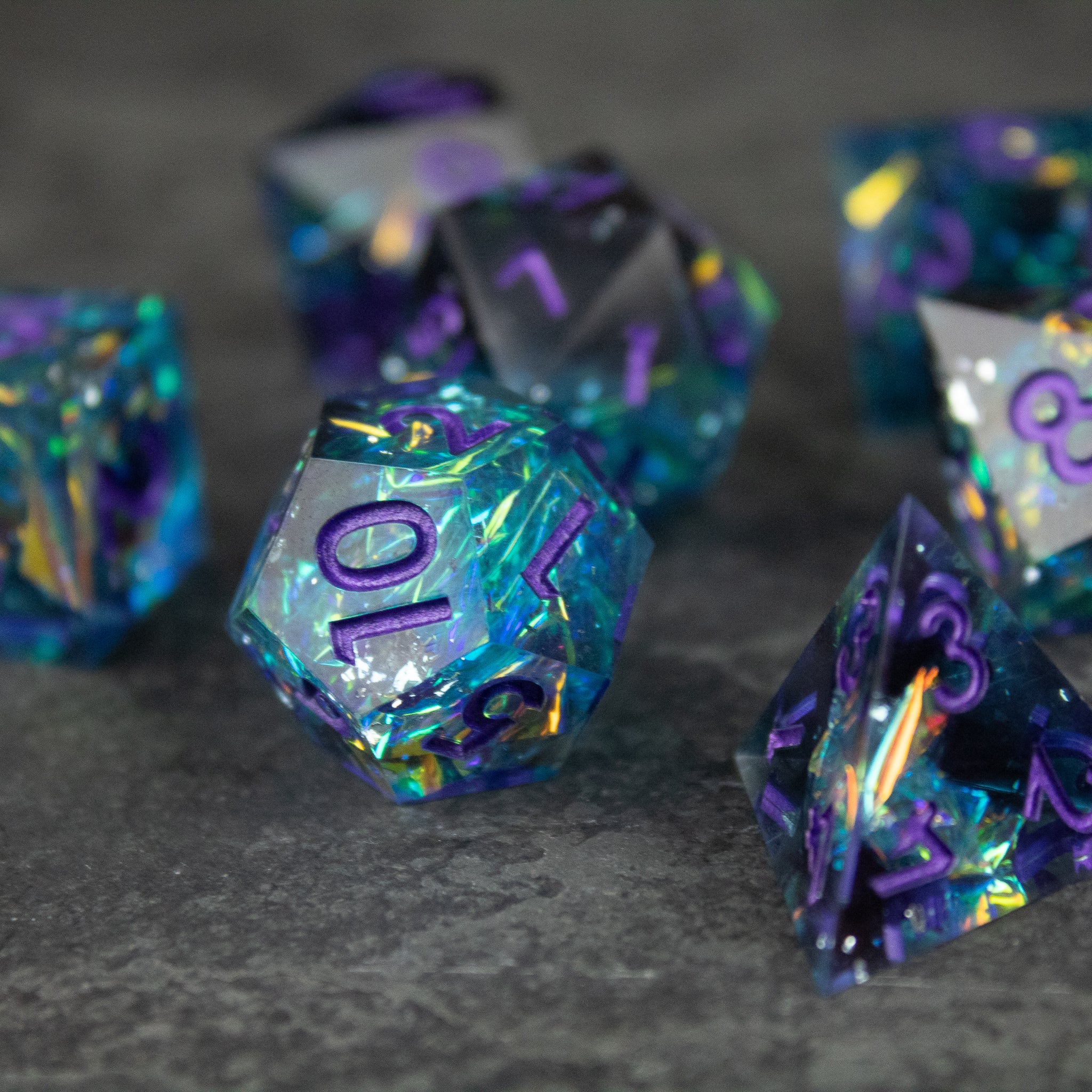 Frostbite Dice Set - Set of black and blue sharp-edged polyhedral dice with translucent, swirling colors and purple numbering.