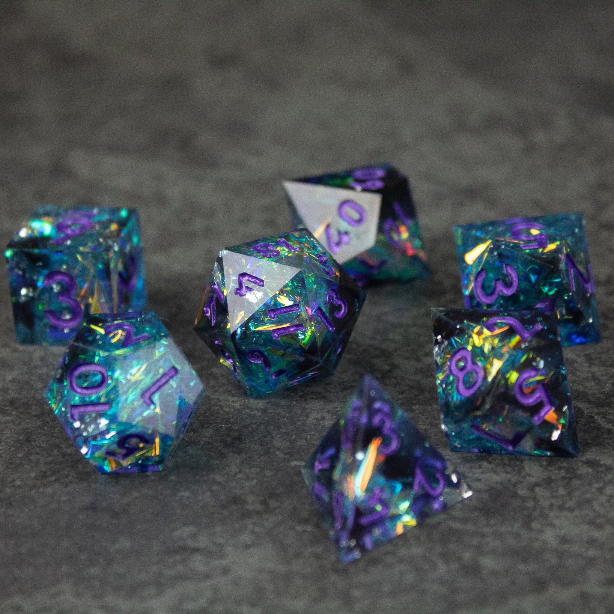 Frostbite Dice Set - Set of translucent black and blue polyhedral dice with sharp edges and holographic shimmer, purple numbers.