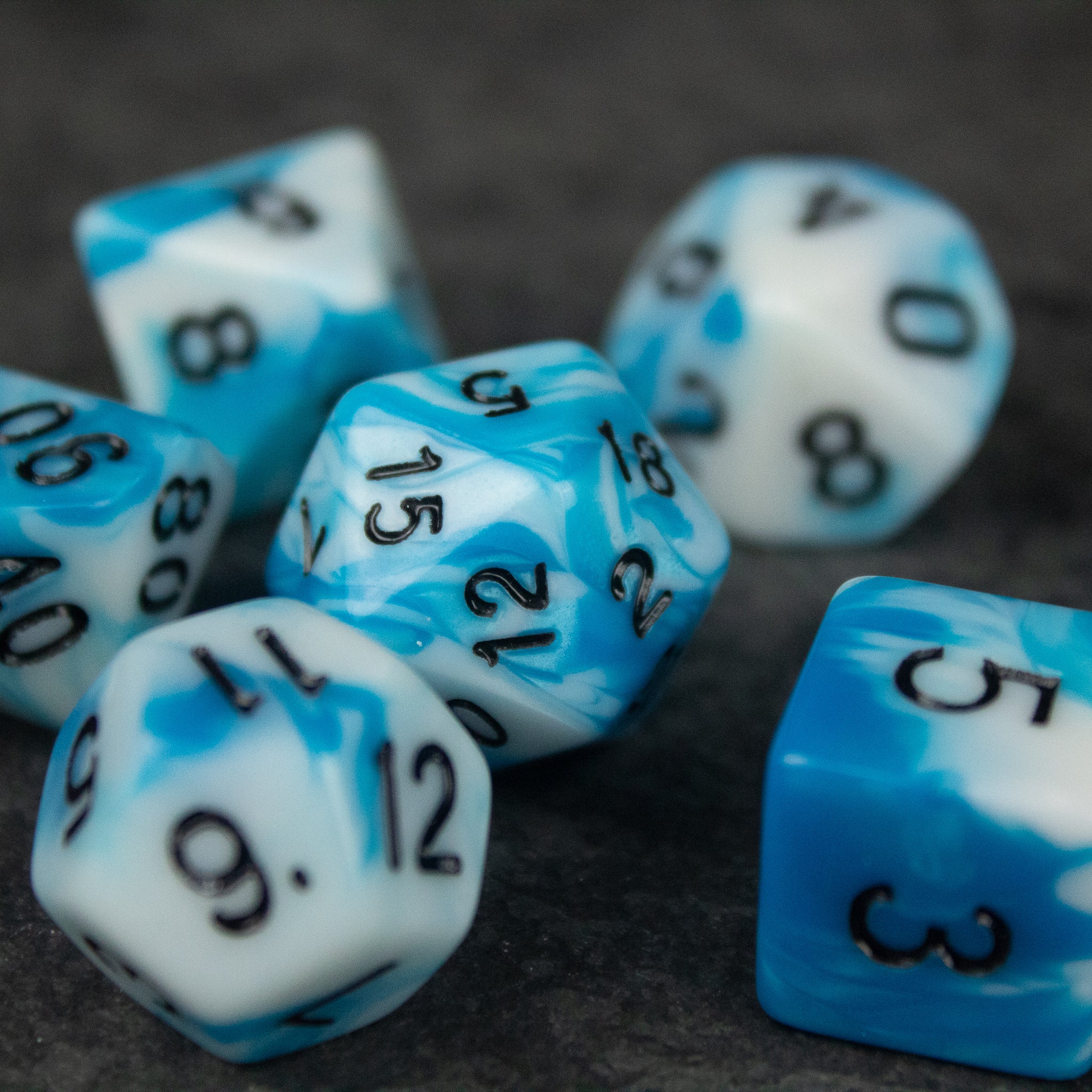 Blue and White Marbled Dice Set - Set of blue and white marbled acrylic polyhedral dice with black numbers on a dark surface.