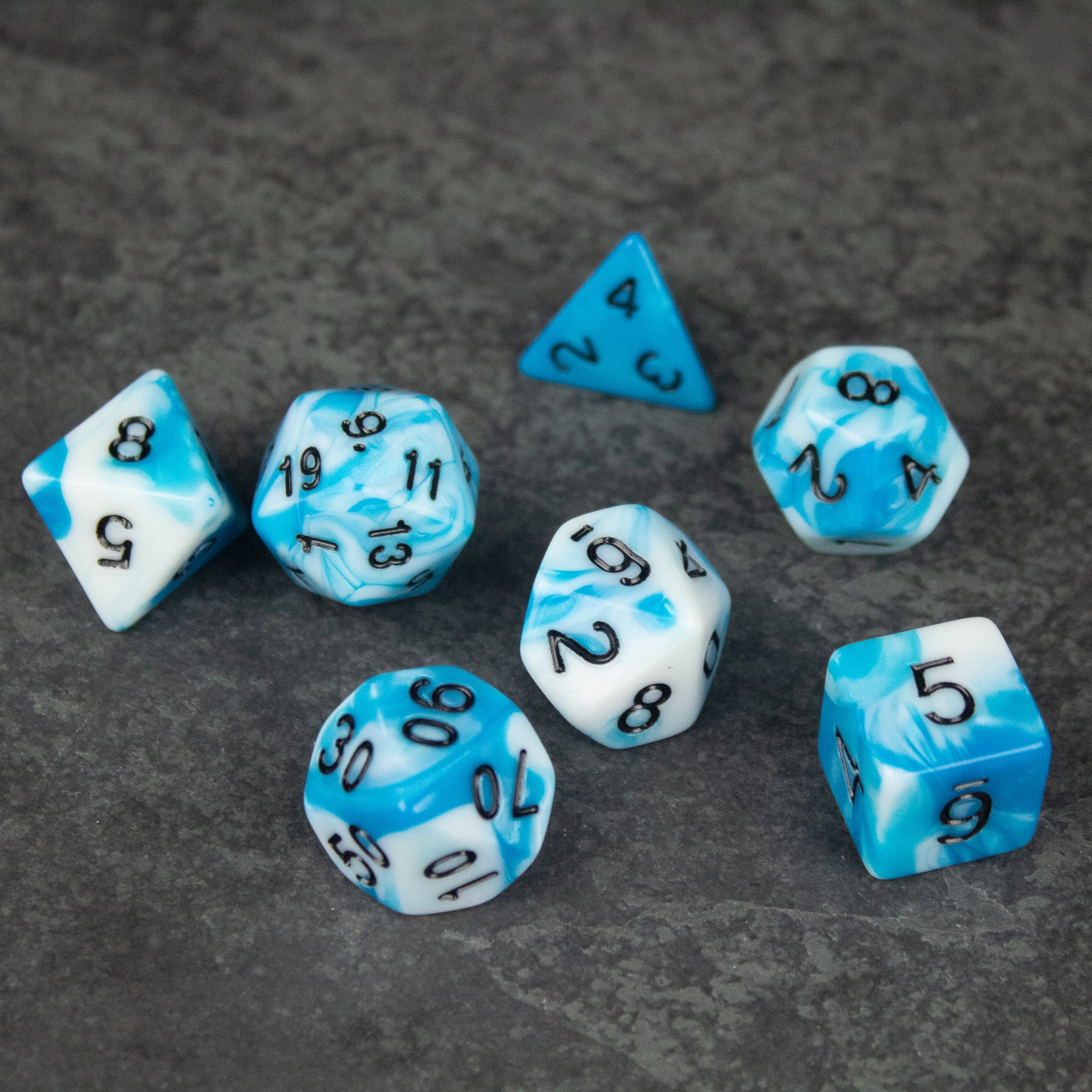 Blue and White Marbled Dice Set - Seven acrylic dice with blue and white marbled patterns, including d4, d6, d8, d10, d12, and d20 shapes with black numbering.