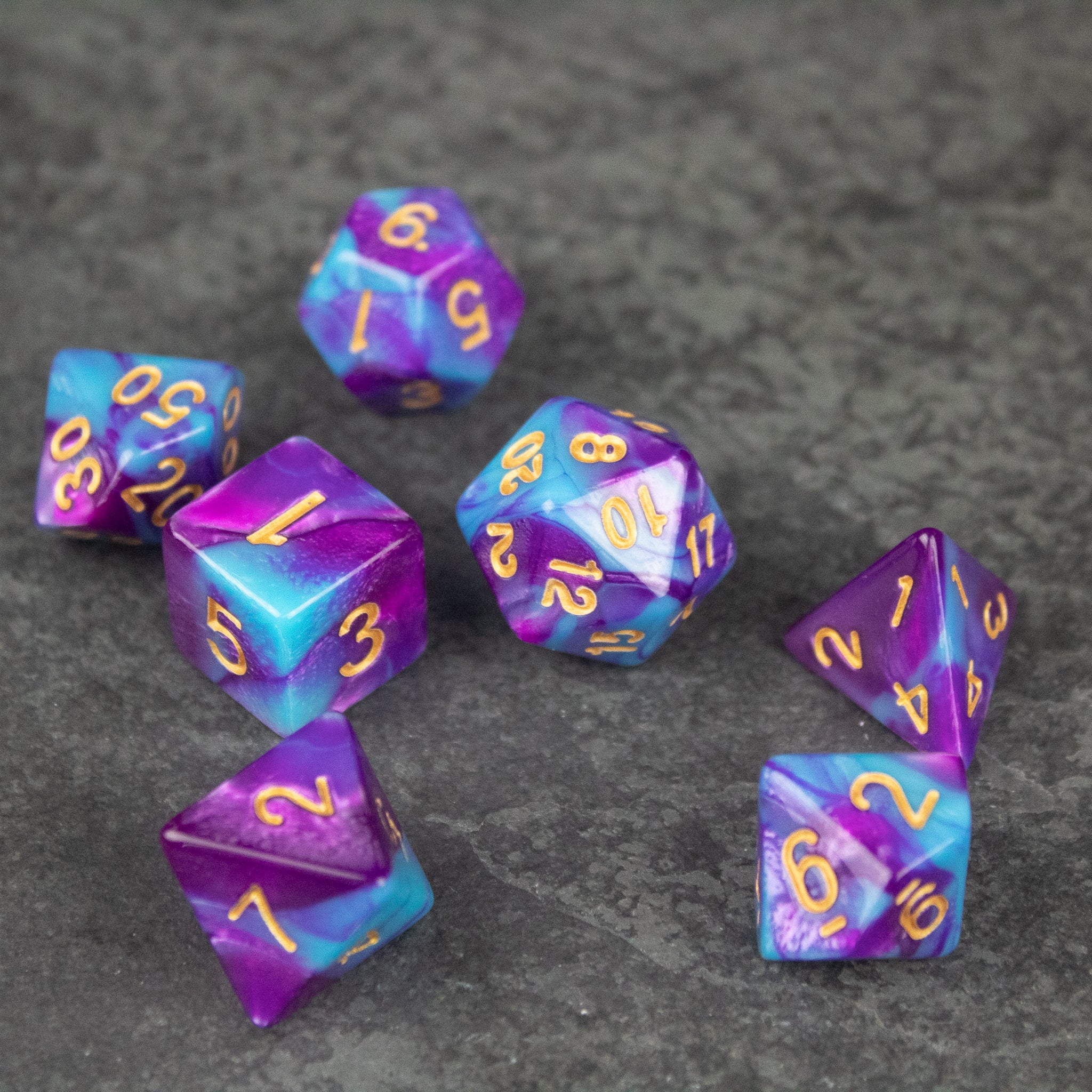 Purple and Blue Marbled Dice Set - Seven purple and blue marbled acrylic dice with gold numbers, featuring various polyhedral shapes.
