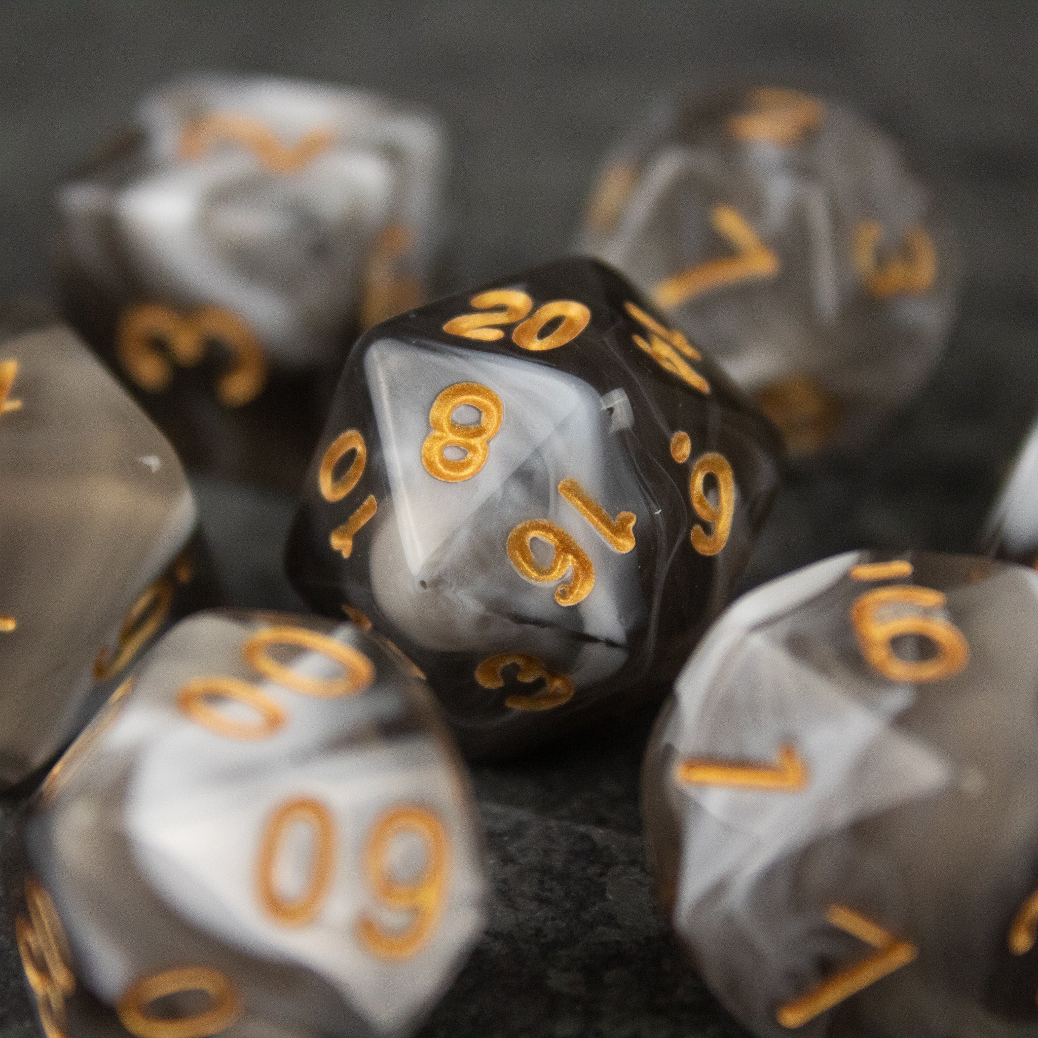 White and Gray Marbled Dice Set - Set of white and gray marbled acrylic polyhedral dice with gold numbers and a black 20-sided die centerpiece.