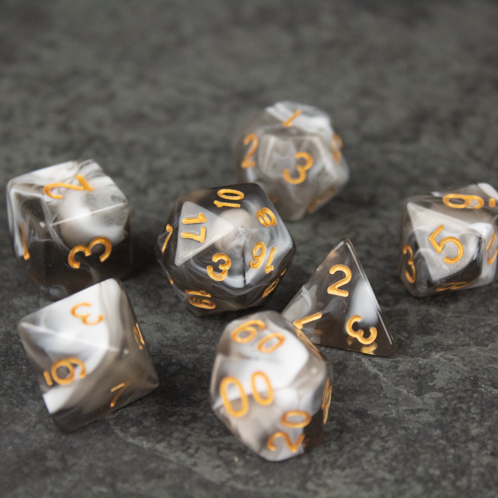 White and Gray Marbled Dice Set - White and gray marbled acrylic dice set with orange numbers on a dark textured surface.