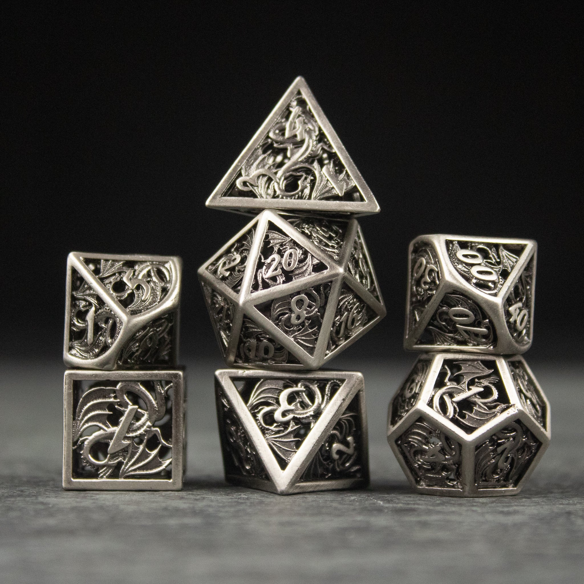 Dragon Cult Hollow Dice Set - Metal hollow polyhedral dice set with intricate dragon designs and filigree details.