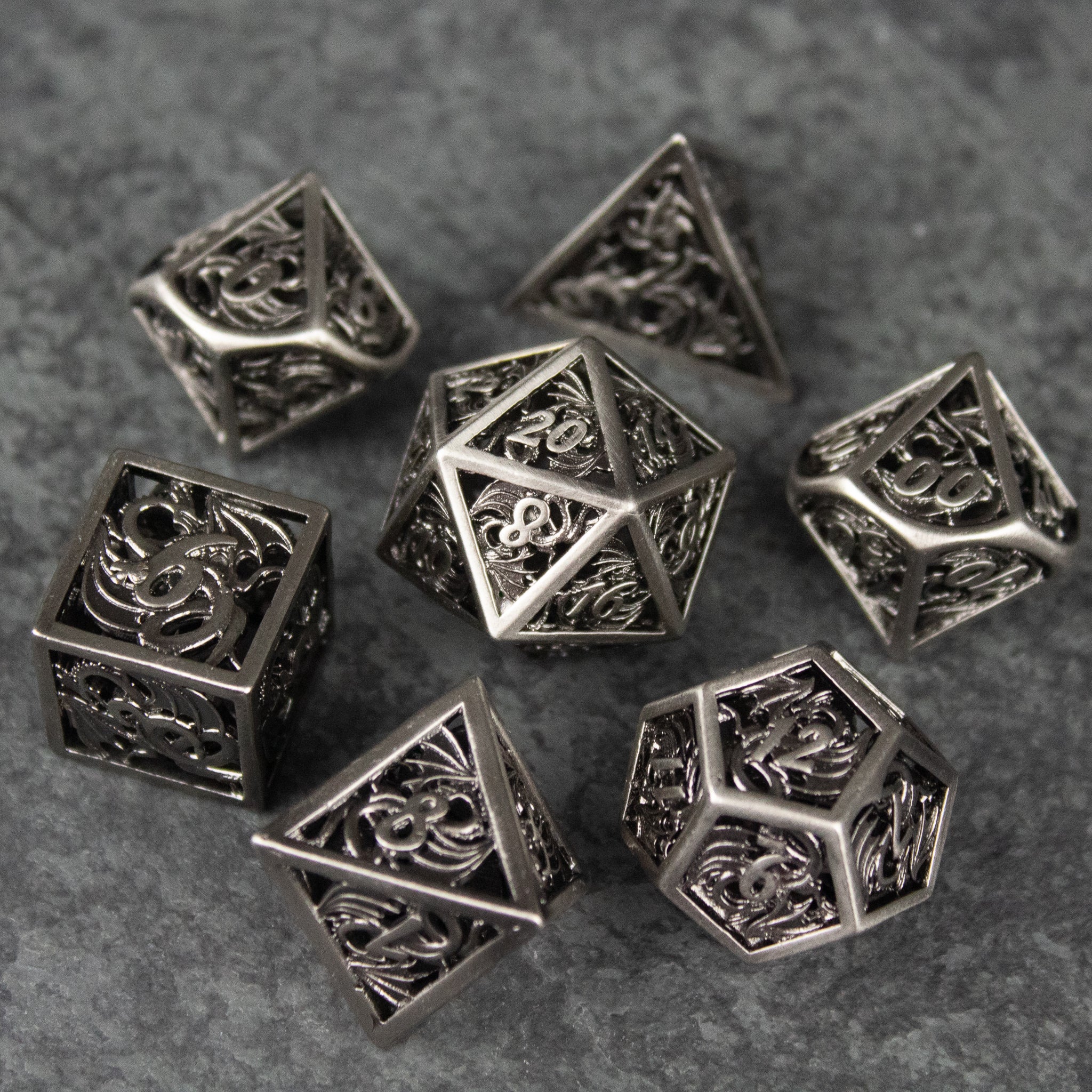 Dragon Cult Hollow Dice Set - Metal hollow polyhedral dice set with intricate dragon and flame designs on each face.