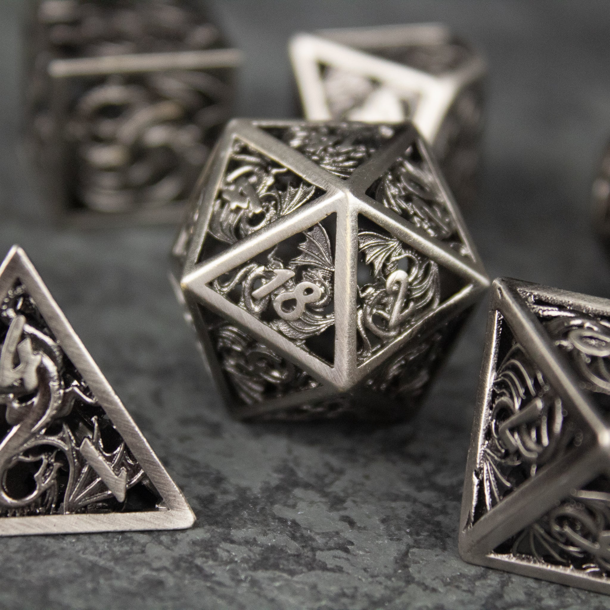 Dragon Cult Hollow Dice Set - Set of hollow metal dice with intricate dragon-themed filigree designs and a dark silver finish.