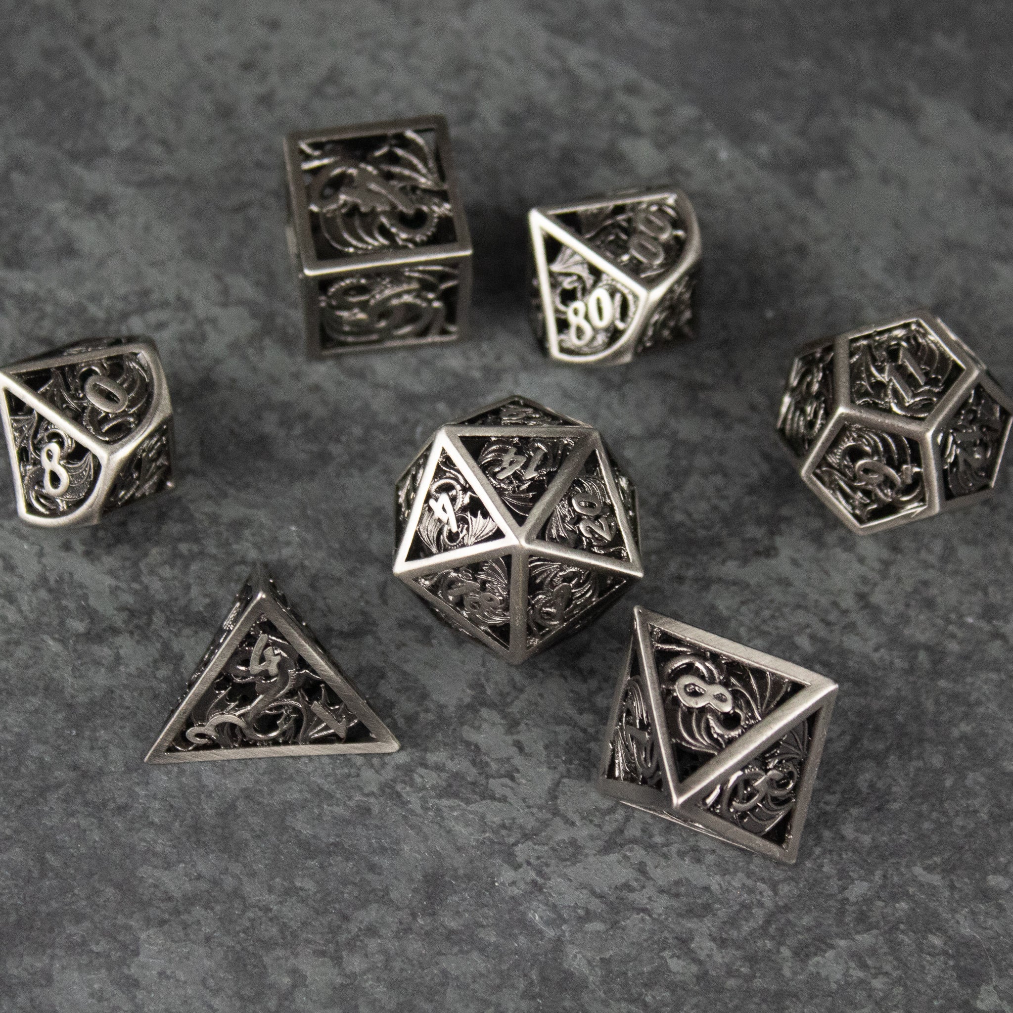 Dragon Cult Hollow Dice Set - Metallic hollow polyhedral dice set with intricate dragon designs in dark silver finish.
