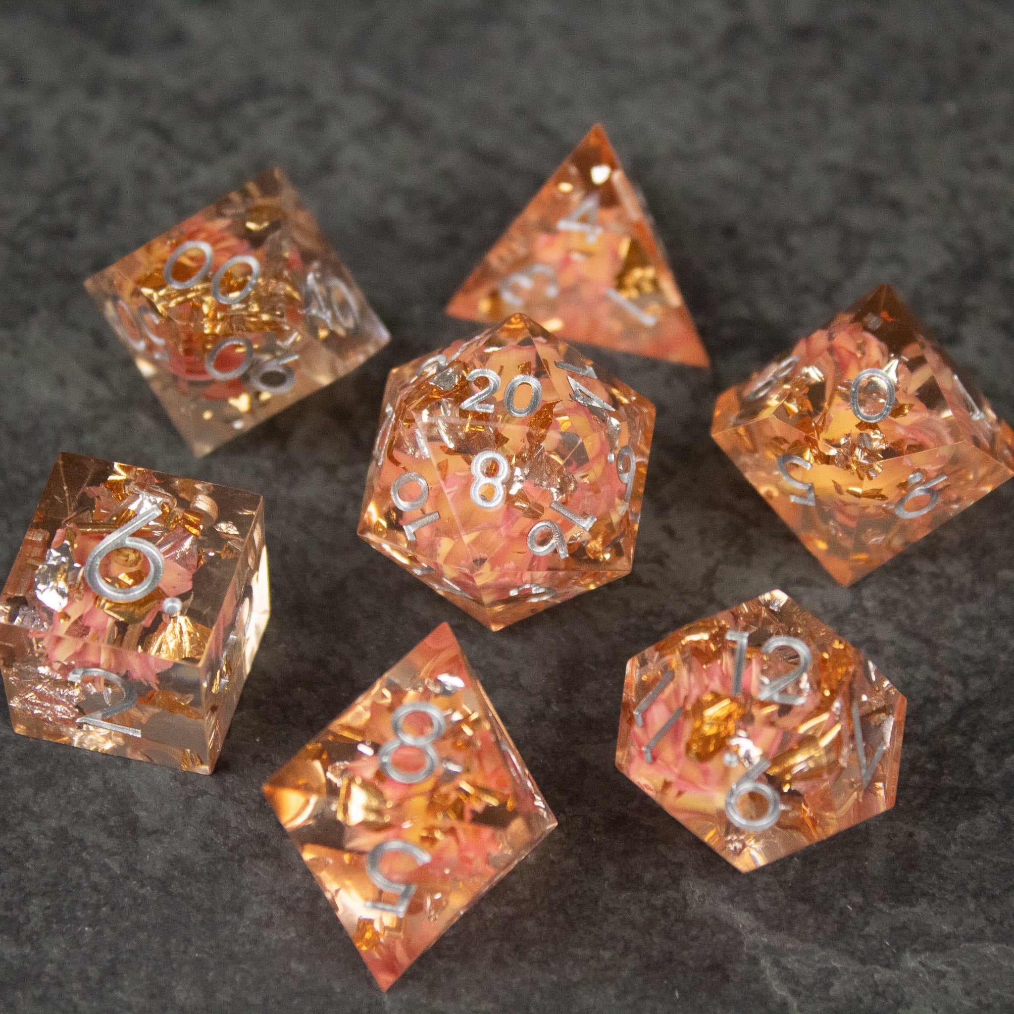Pink Flower Sharp Edge Dice Set - Translucent pink sharp-edged dice set with embedded pink flowers and silver numbers.