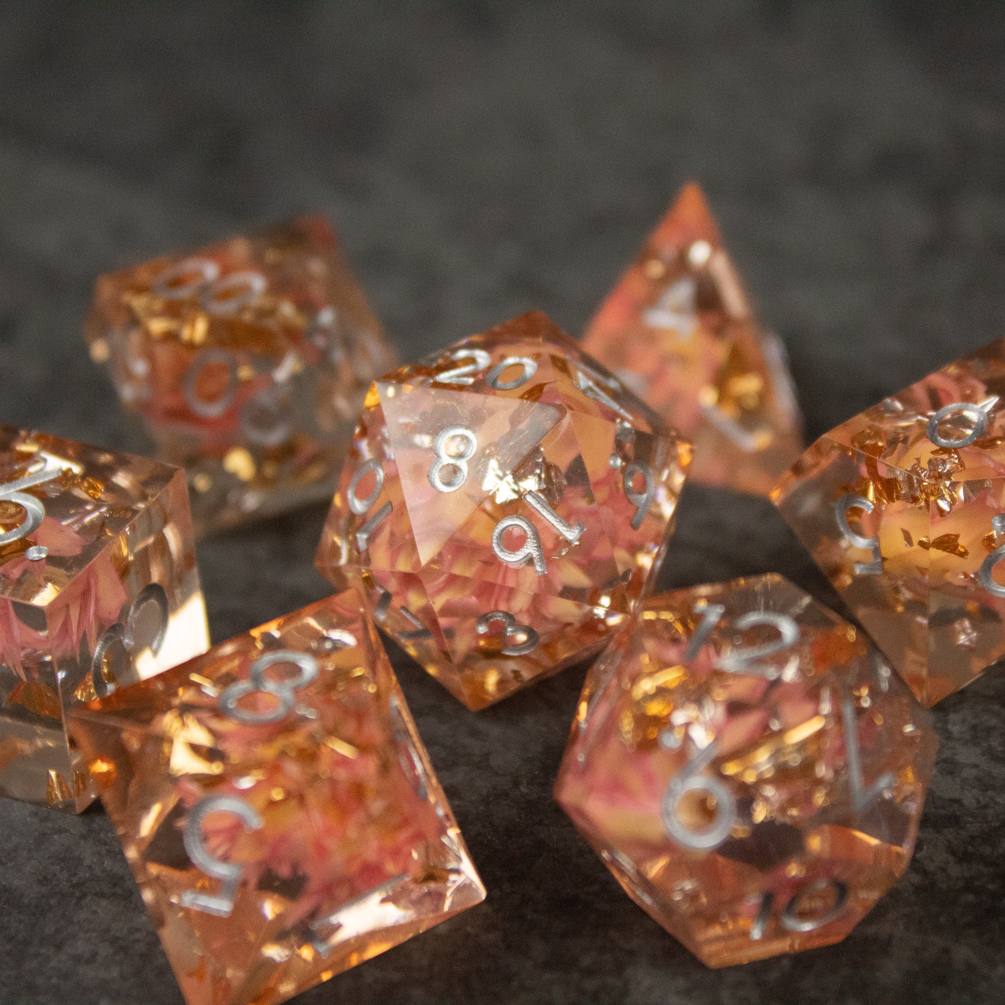 Pink Flower Sharp Edge Dice Set - Set of translucent pink sharp-edged polyhedral dice with embedded flower petals and white numbering.