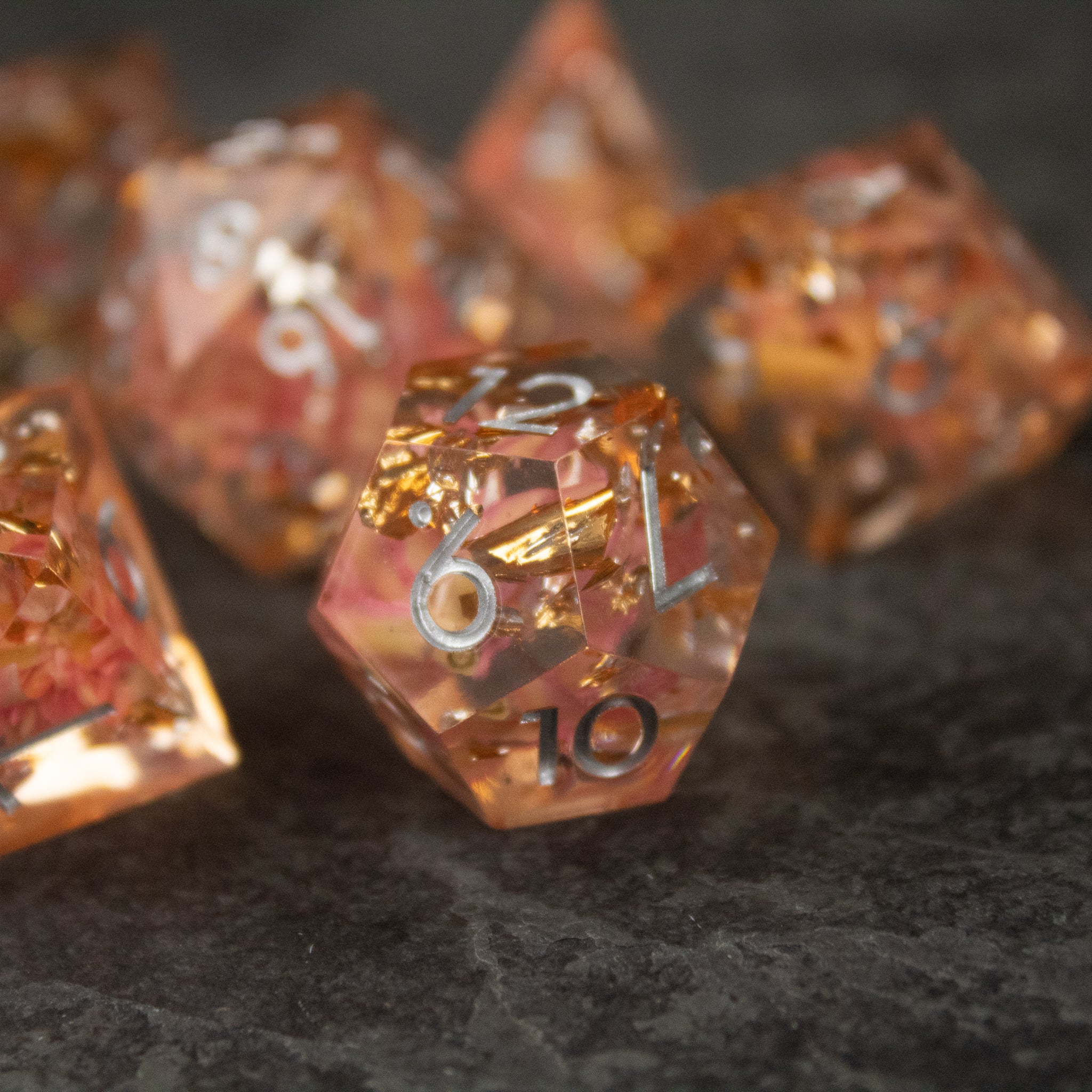 Pink Flower Sharp Edge Dice Set - Transparent pink d20 dice with sharp edges and embedded delicate flower petals, numbered in white.