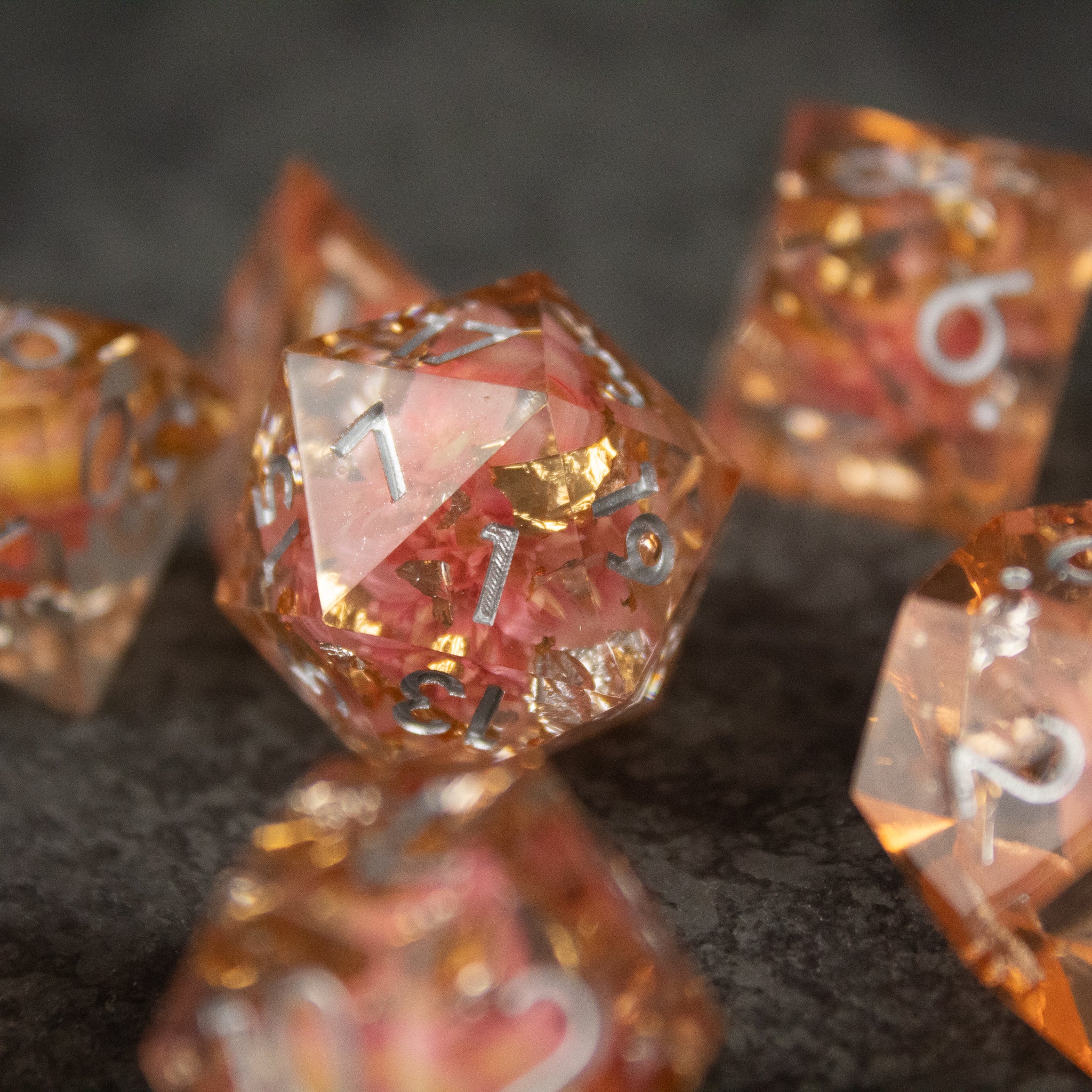 Pink Flower Sharp Edge Dice Set - Set of pink transparent sharp-edged polyhedral dice with gold flower inclusions and white numbers.