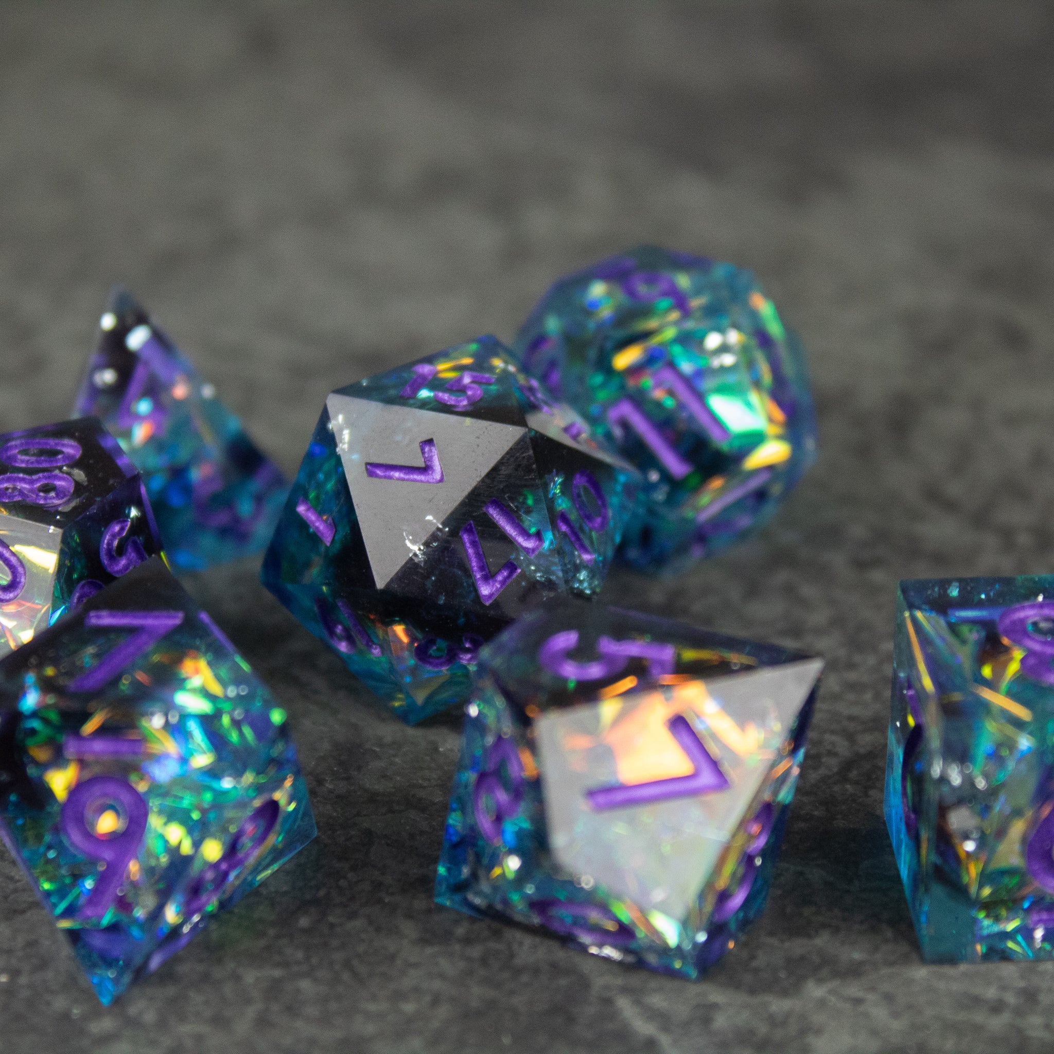 Frostbite Dice Set - Iridescent blue and black sharp-edged dice with angular facets and purple numbering.