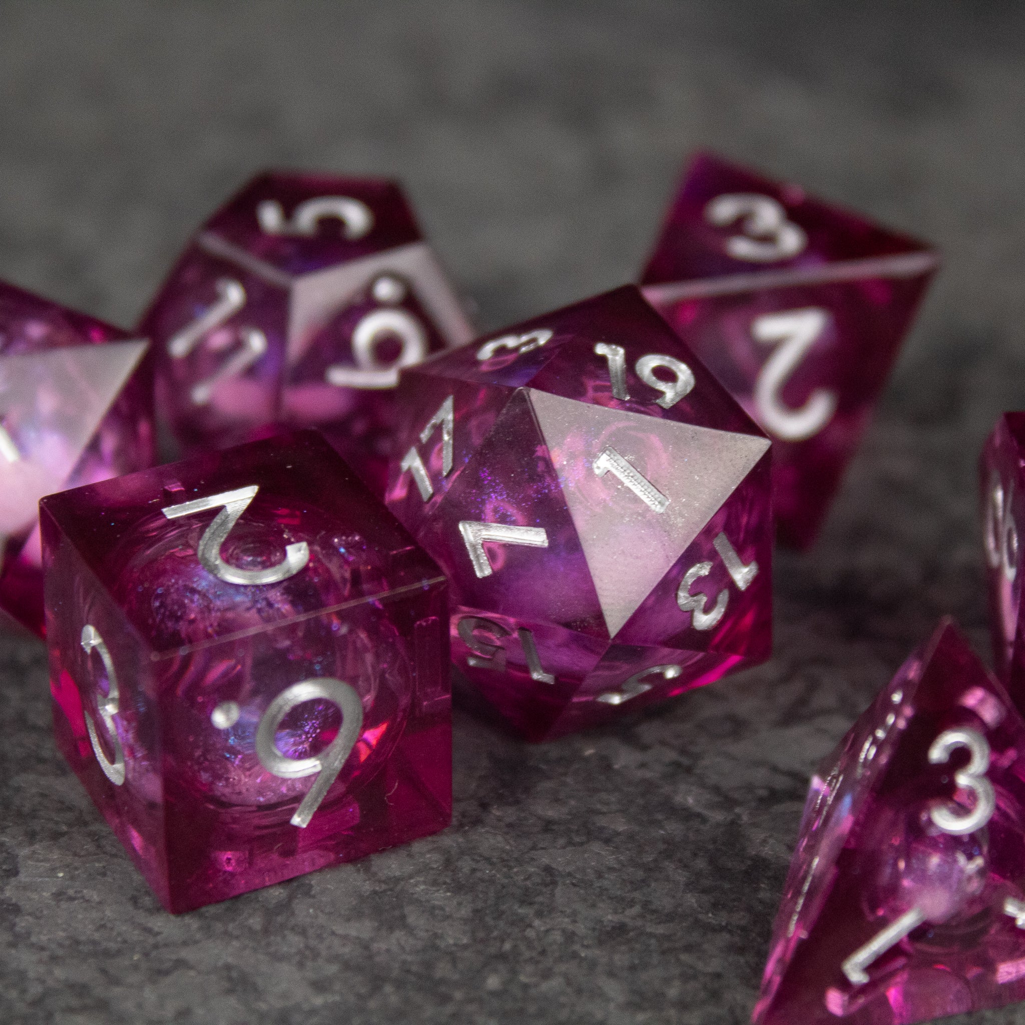 Magic Wine - Liquid Core Dice Set - Set of translucent red liquid core dice with sharp edges and white numbering on dark textured surface.