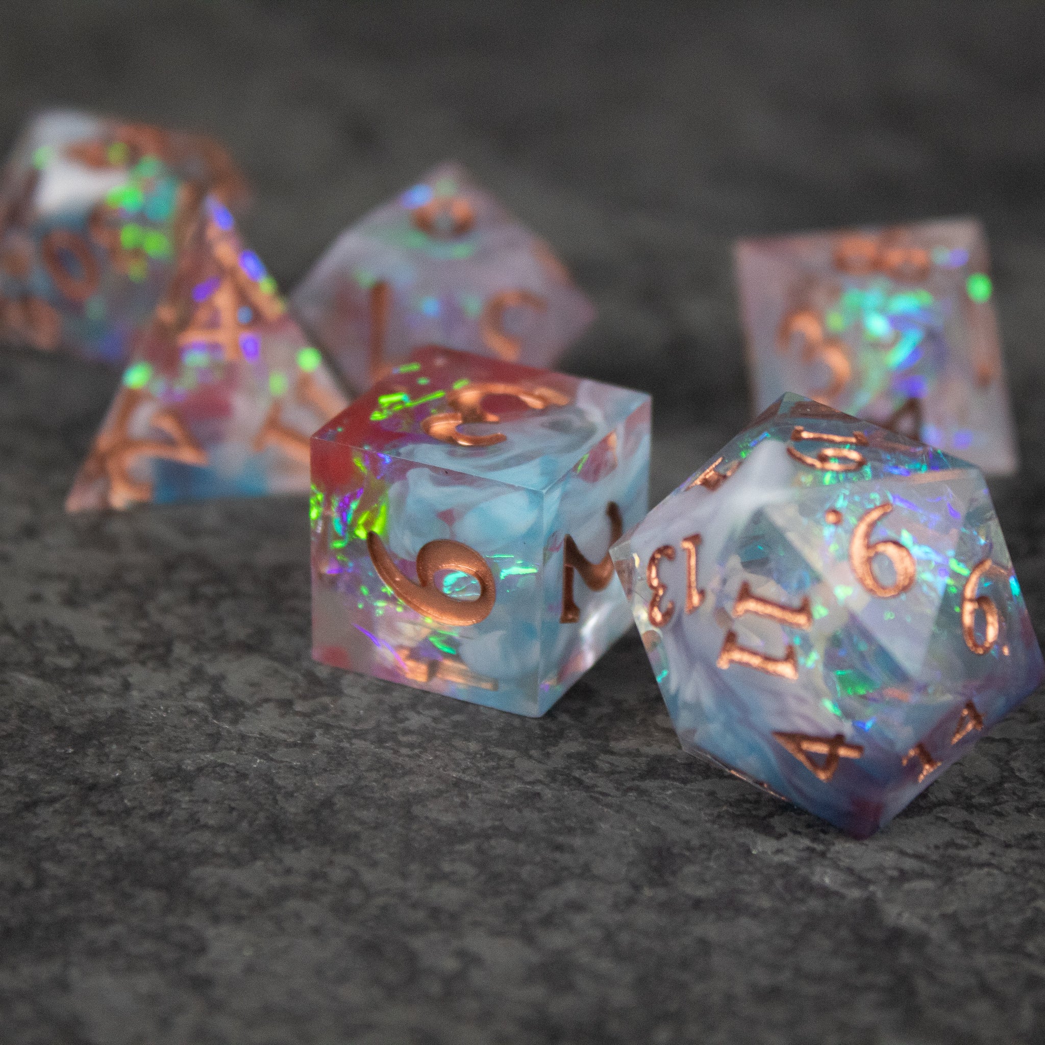 Divination Dice Set - Translucent blue and purple polyhedral dice set with copper metallic numbers and sharp edges on dark textured surface.