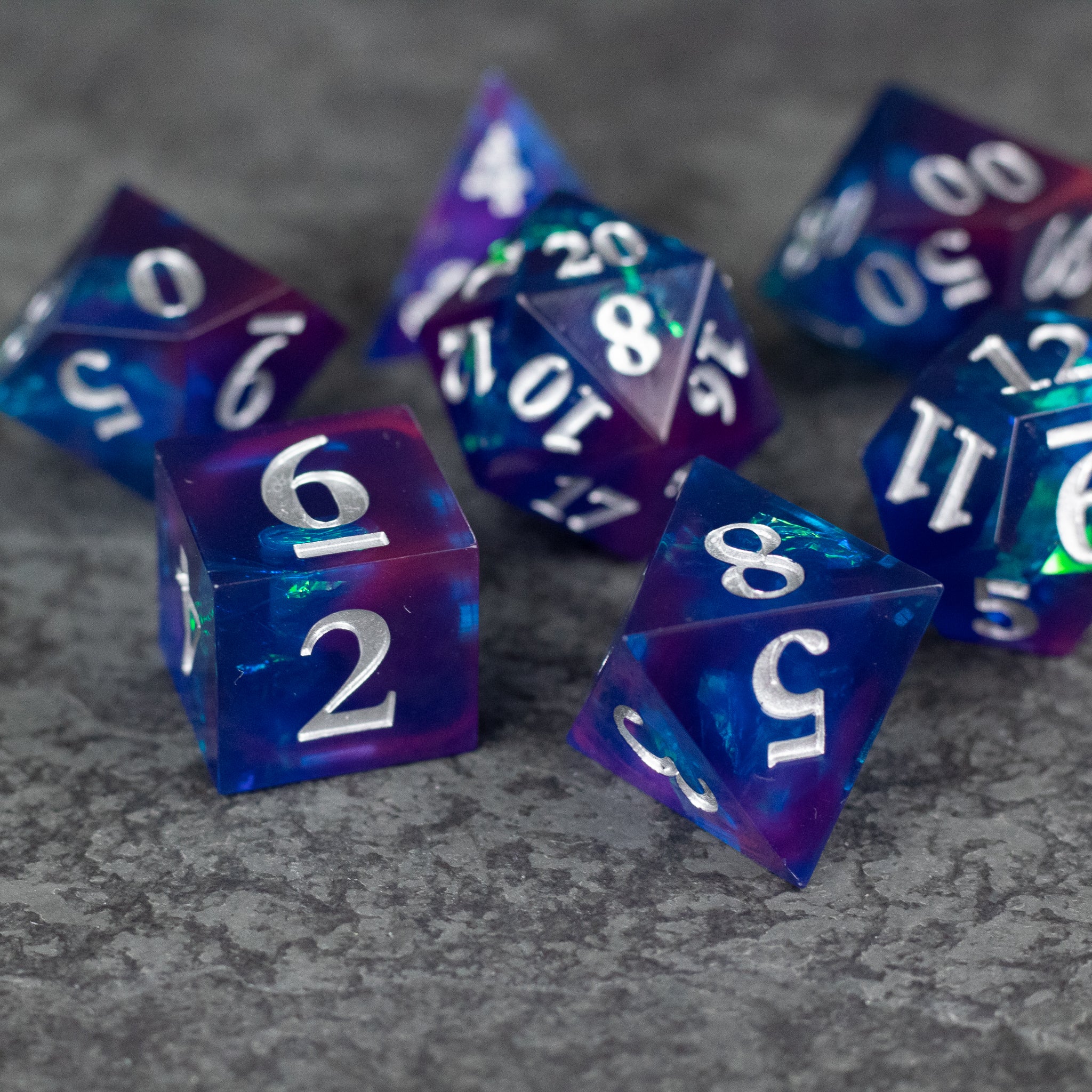 Midnight Blue Dice Set - Set of sharp-edged dice in translucent midnight blue with white numbering on a textured dark surface.