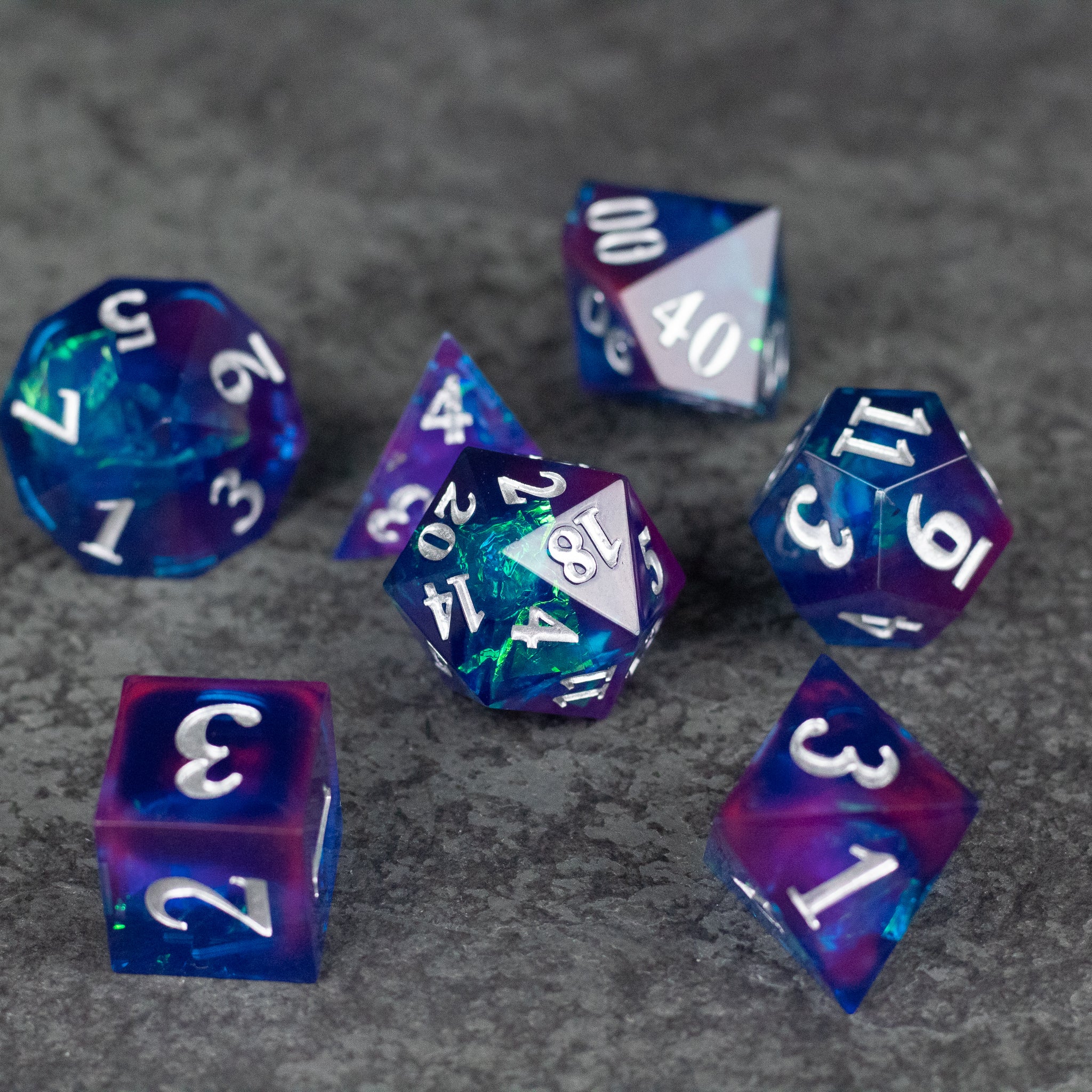 Midnight Blue Dice Set - Set of seven sharp-edged dice in midnight blue and purple with white numbering on a gray surface.