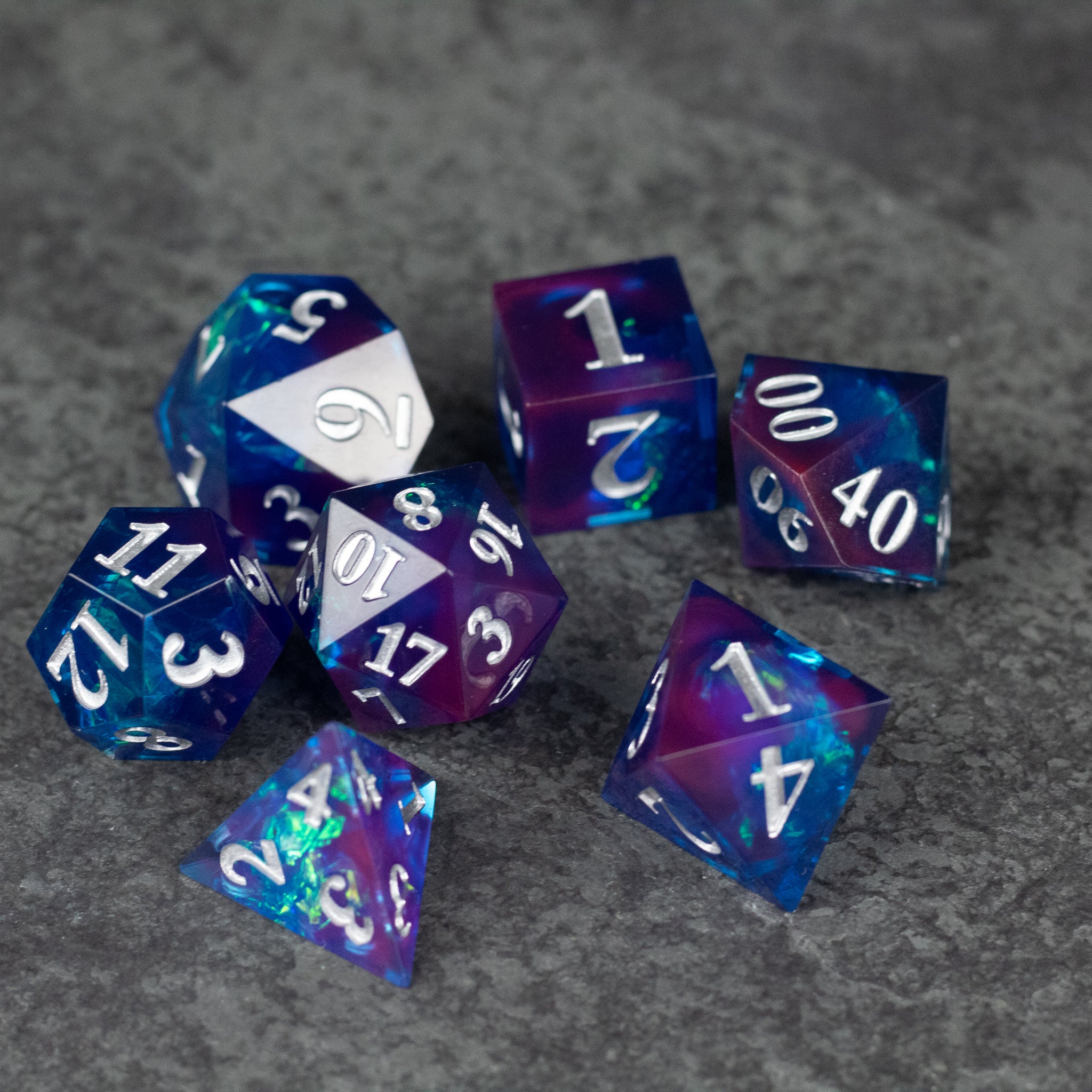 Midnight Blue Dice Set - Set of seven sharp-edged polyhedral dice in midnight blue and purple with white numbers.
