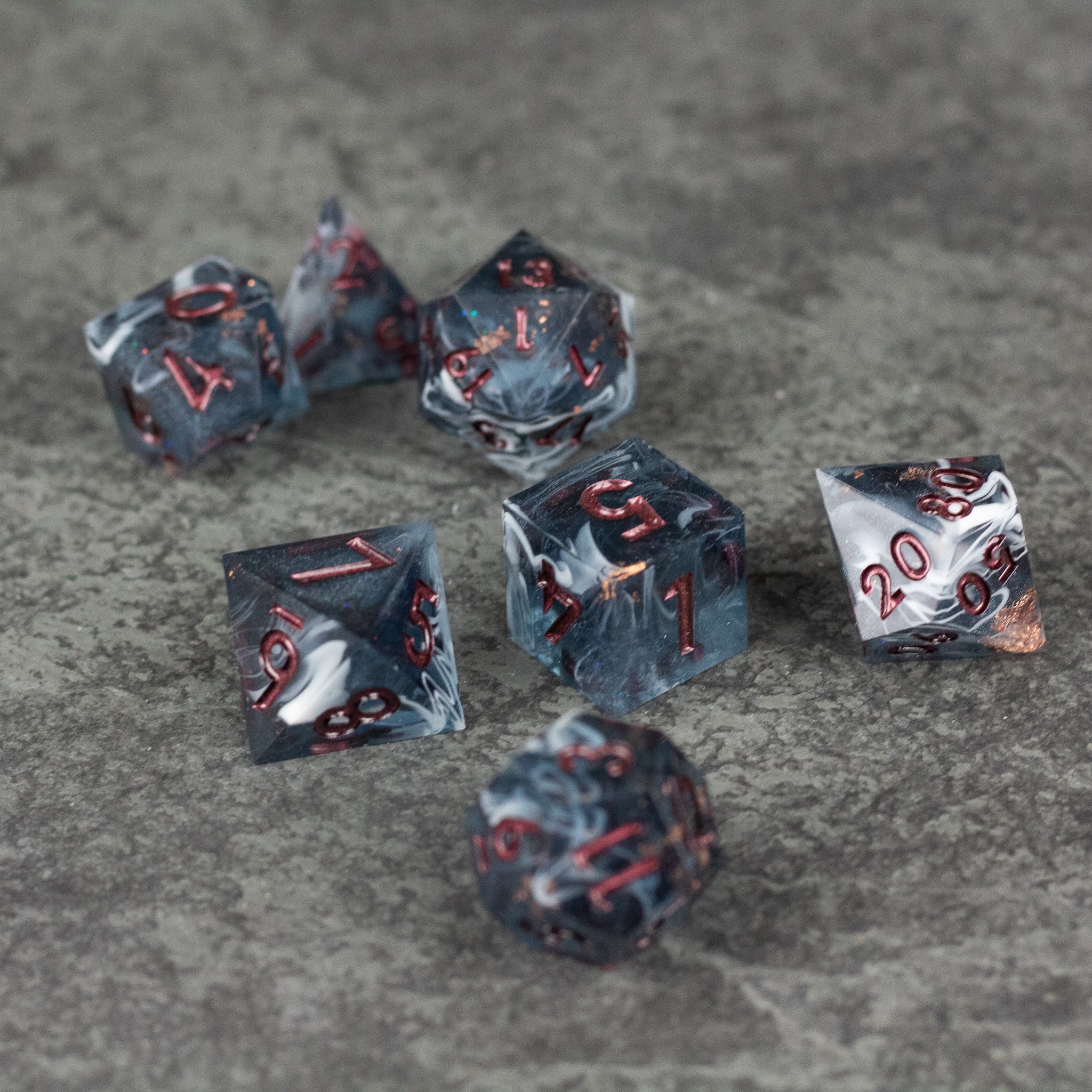 Omen Dice Set - Black and gray sharp-edged dice set with red numbers on textured surface.