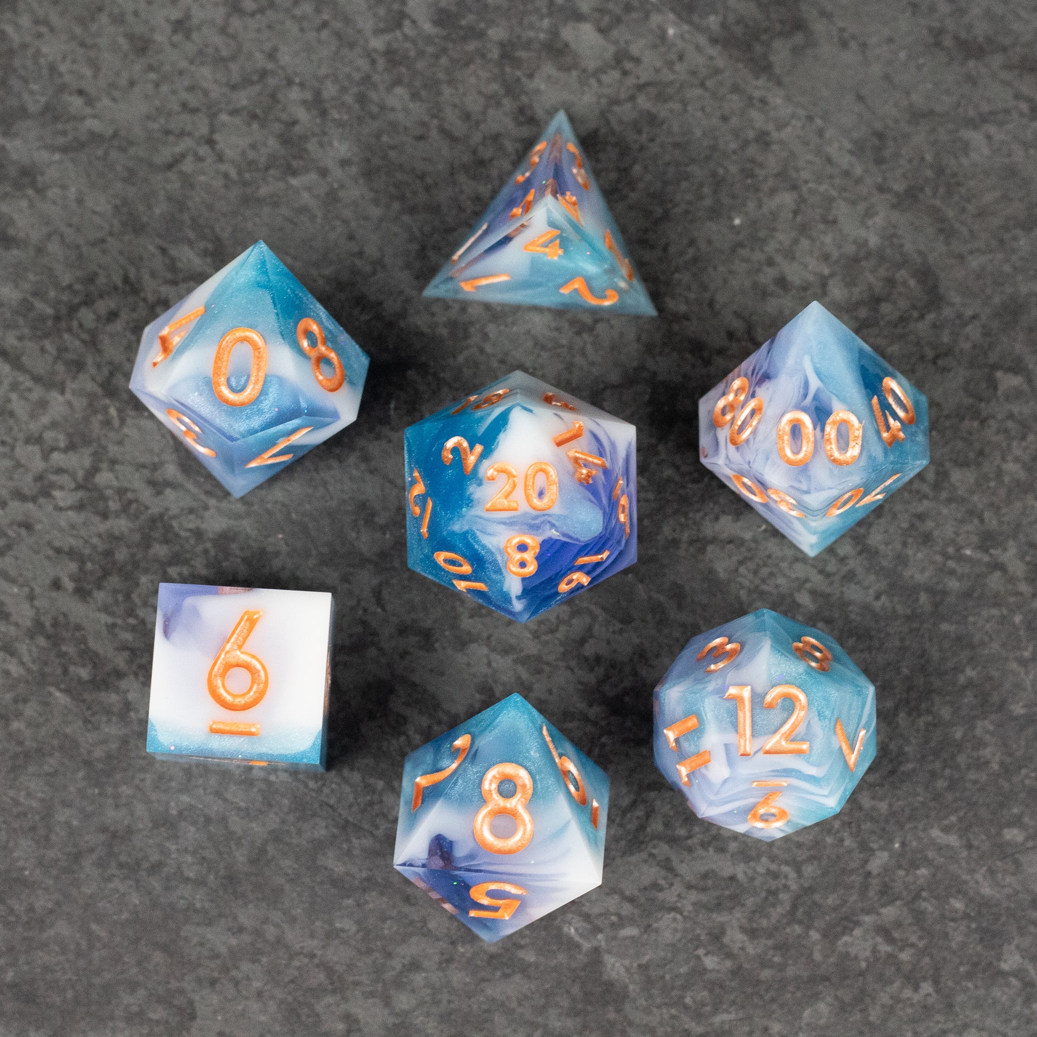 Cloudscape Dice Set - Seven-piece blue and white sharp-edged dice set with orange numbers and a marbled cloud-like pattern.