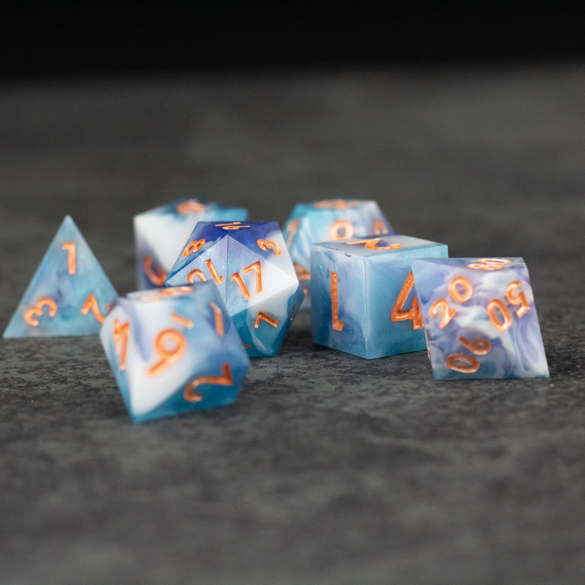 Cloudscape Dice Set - Translucent blue and white sharp-edged polyhedral dice set with orange numbering.