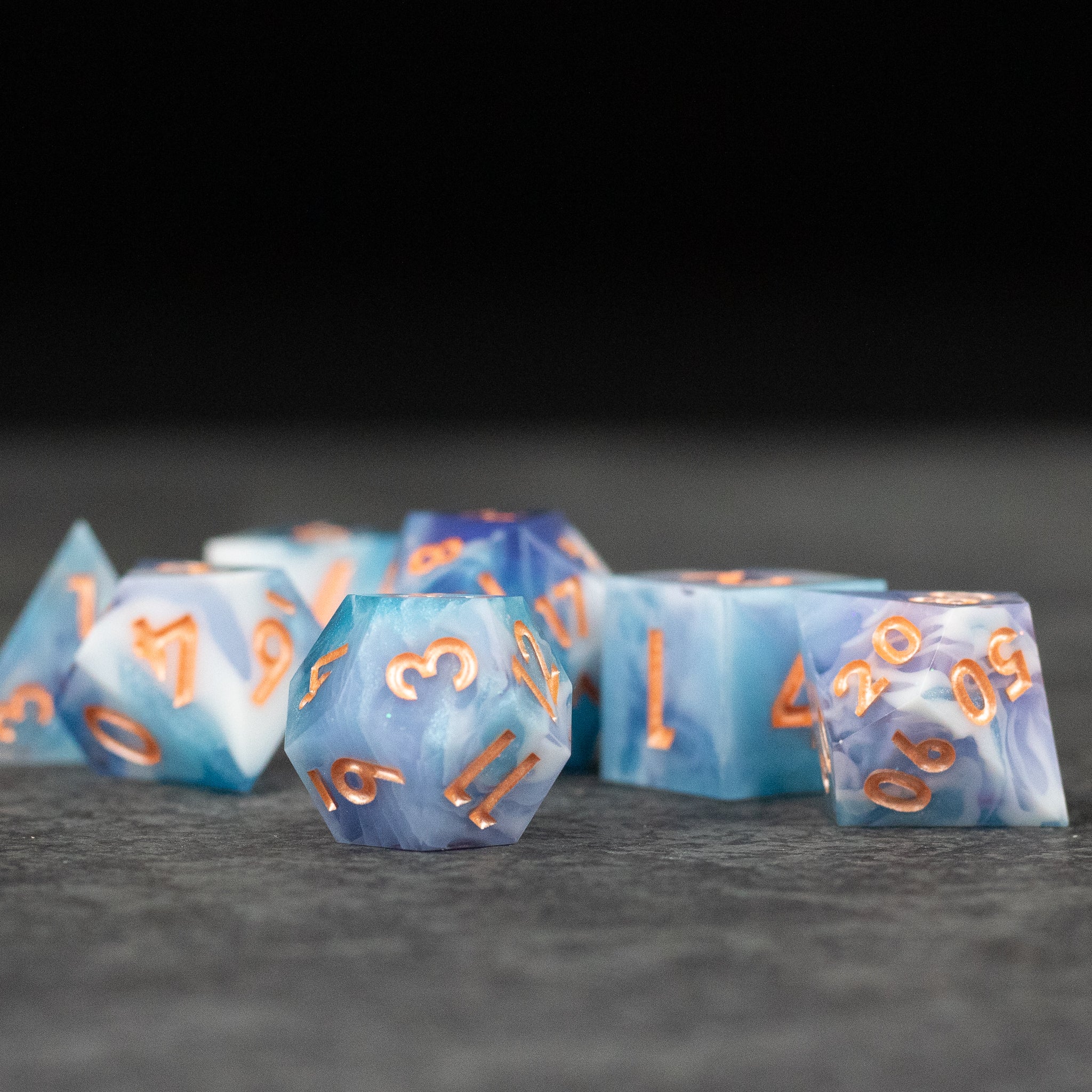 Cloudscape Dice Set - Set of blue and white sharp-edged polyhedral dice with orange numbers, translucent design.
