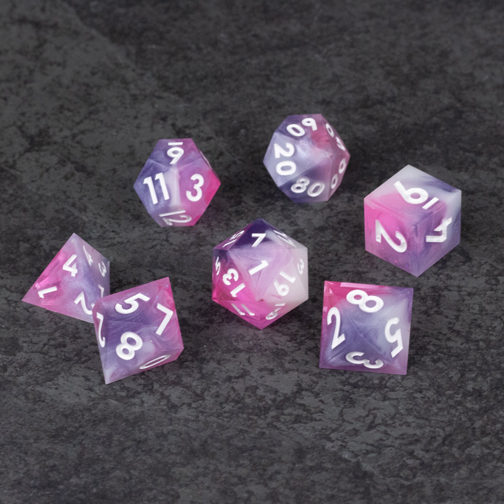Melody Dice Set - Seven translucent pink polyhedral dice with sharp edges and white numbering on a dark textured surface.