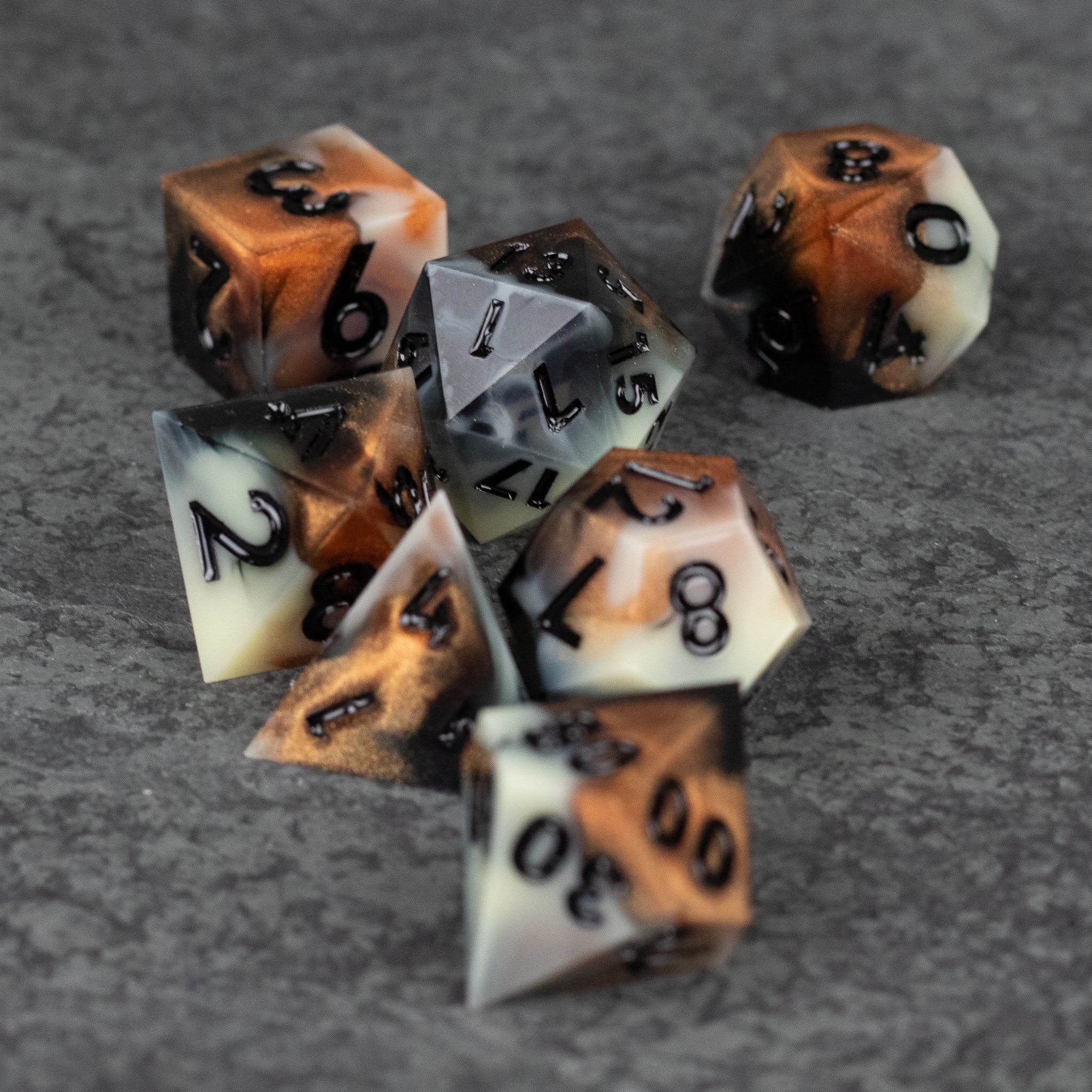 Dwarven Delight Dice Set - Seven black-edged polyhedral dice with sharp edges, featuring a marbled blend of brown, white, and black colors with black.
