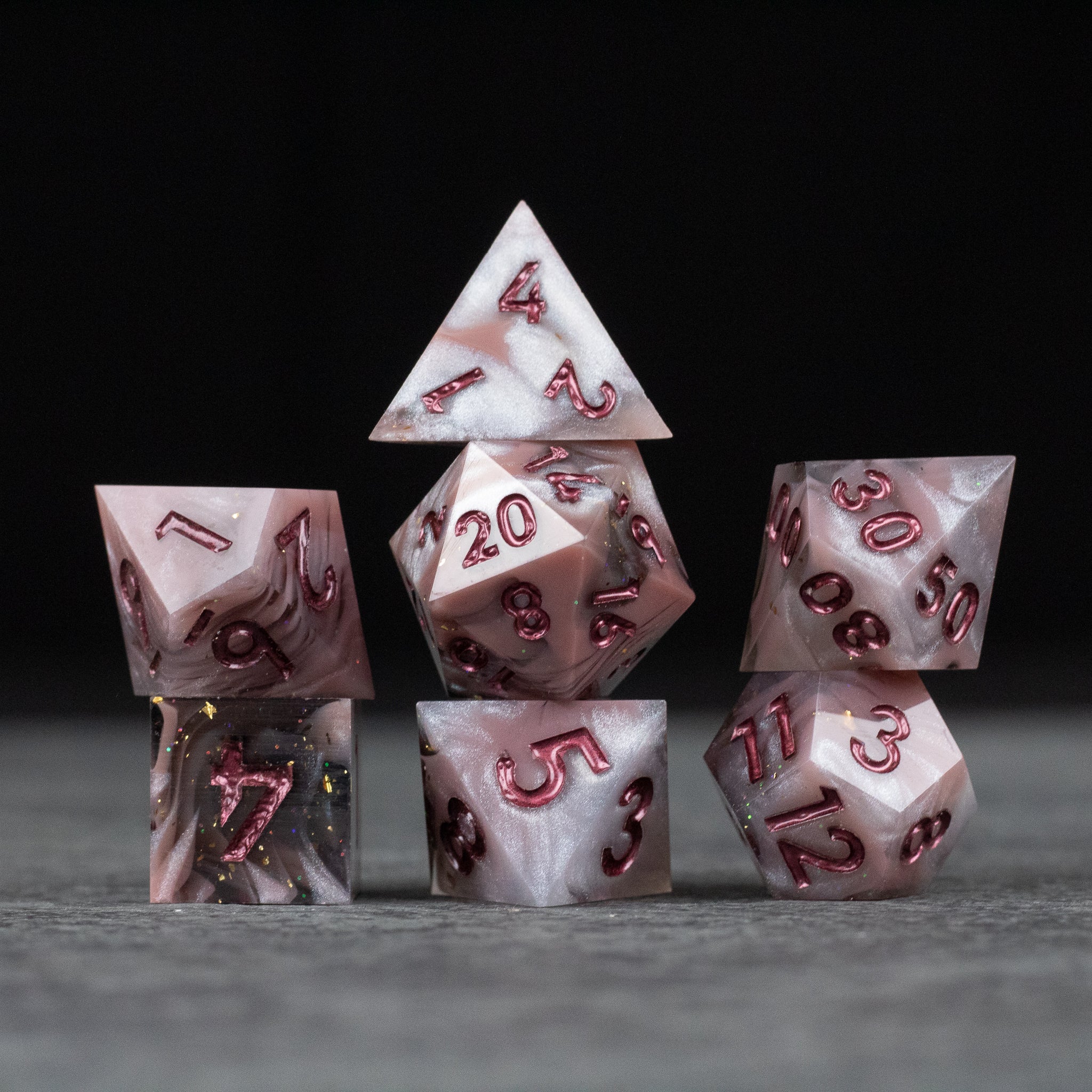 Rosestone Dice Set - Seven white and red sharp-edged polyhedral dice with red numbers arranged on a gray surface.