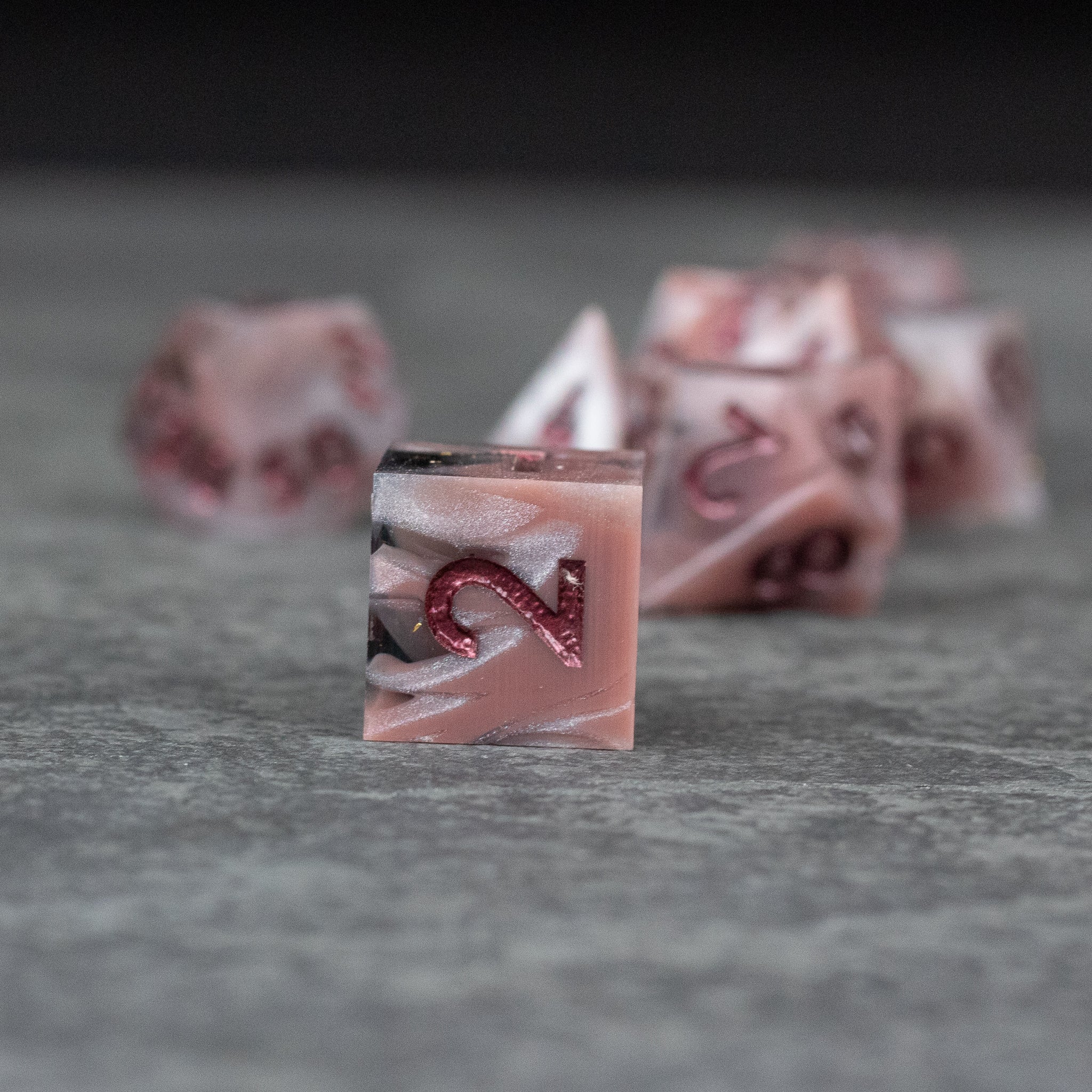 Rosestone Dice Set - Red and white marbled sharp-edged polyhedral dice set with black accent swirls.