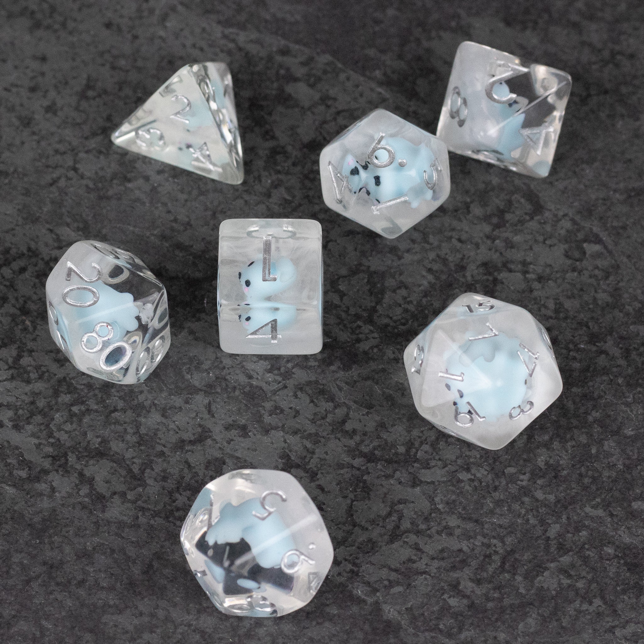 Blue Seal Dice Set - Seven translucent blue polyhedral dice with black numbers and seal illustrations inside, arranged on a dark surface.