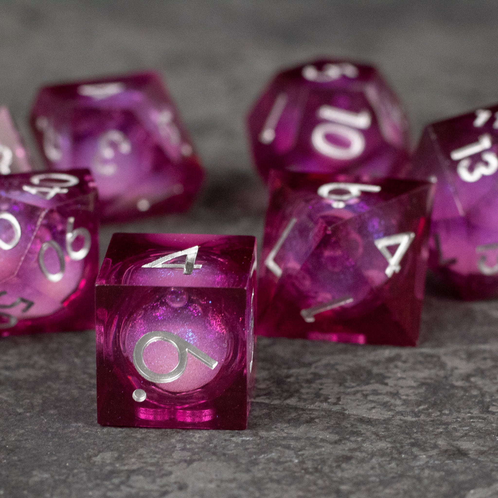 Magic Wine - Liquid Core Dice Set - Set of translucent deep red sharp-edged polyhedral dice with visible liquid core and white numbering.