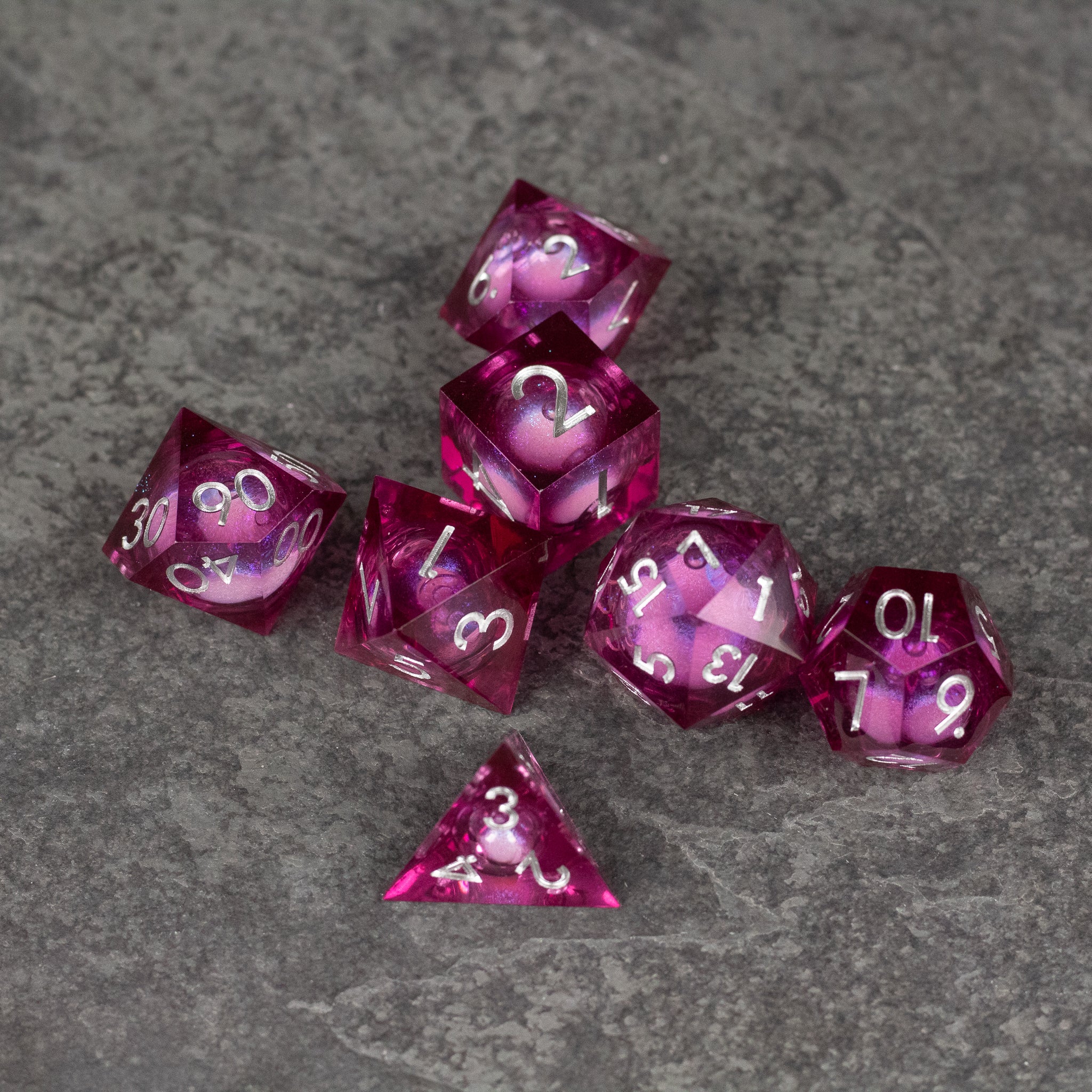 Magic Wine - Liquid Core Dice Set - Set of red translucent polyhedral dice with sharp edges and white numbers, featuring liquid core design.