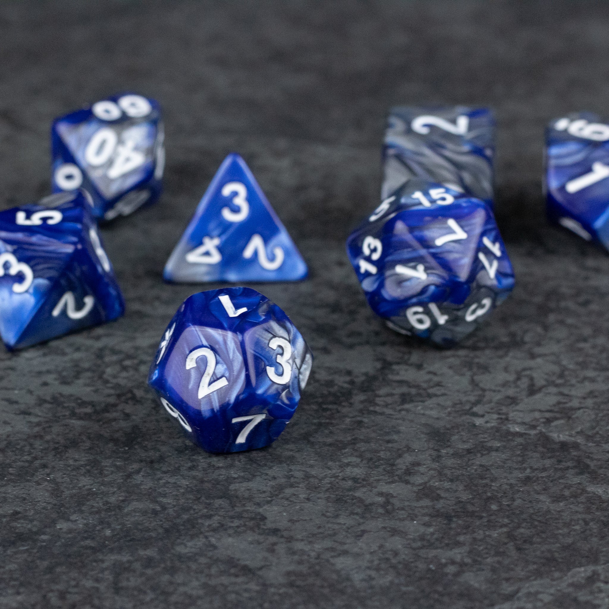 Royal Blue and Silver Acrylic Dice Set - Set of royal blue acrylic dice with silver numbering, various polyhedral shapes on dark textured surface.