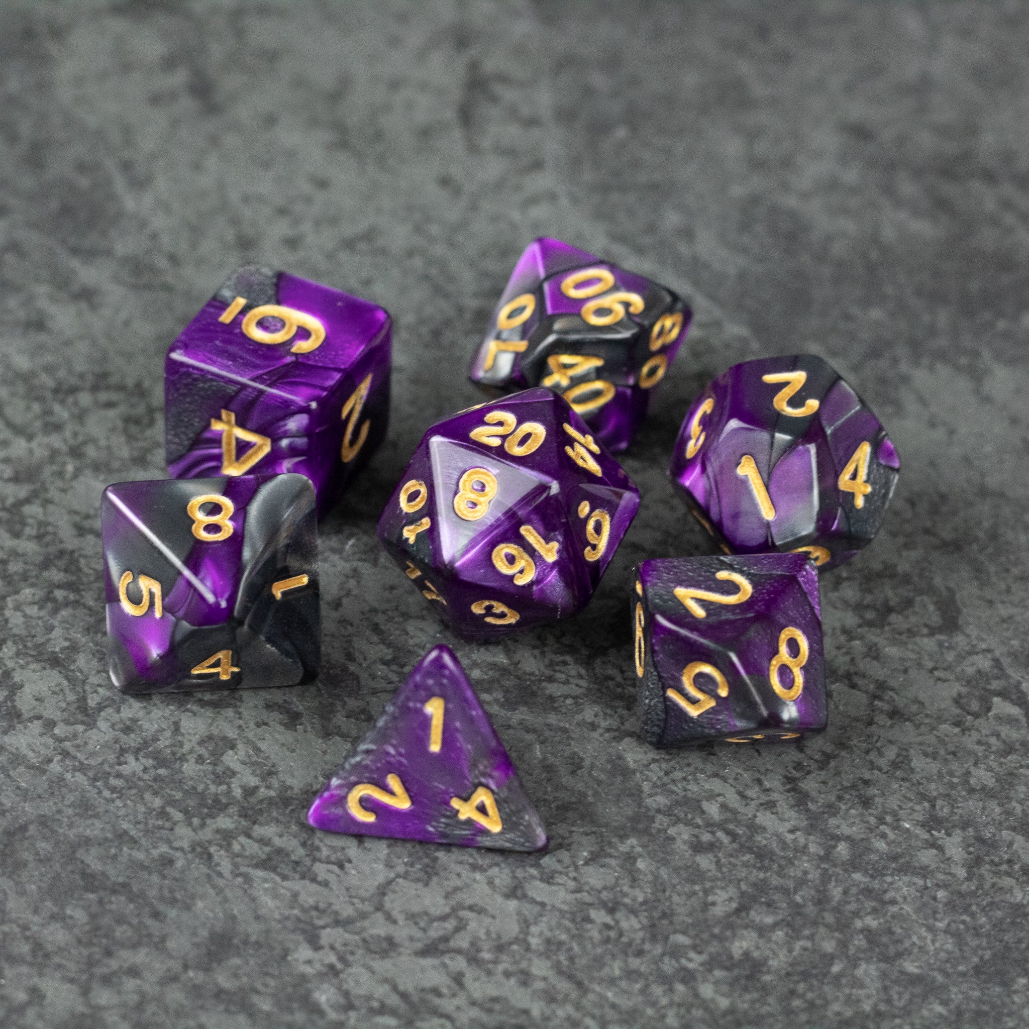 Purple and Black Marbled Dice Set - Set of seven purple and black marbled acrylic dice with gold numbering on gray surface.