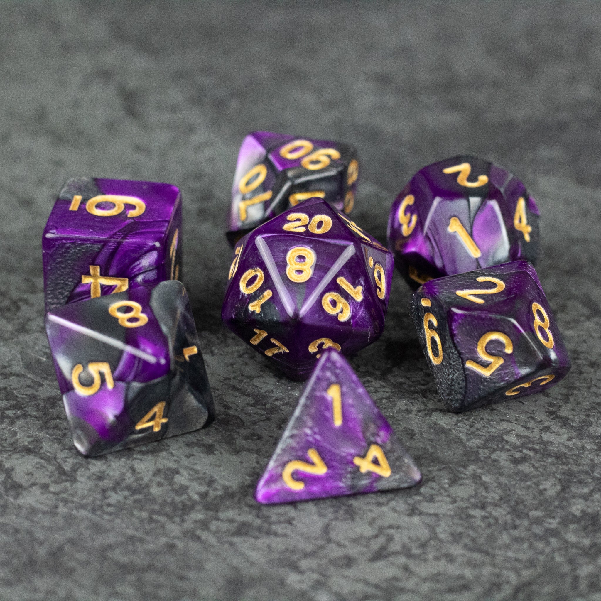 Purple and Black Marbled Dice Set - Purple and black marbled acrylic dice set with gold numbering on gray surface.