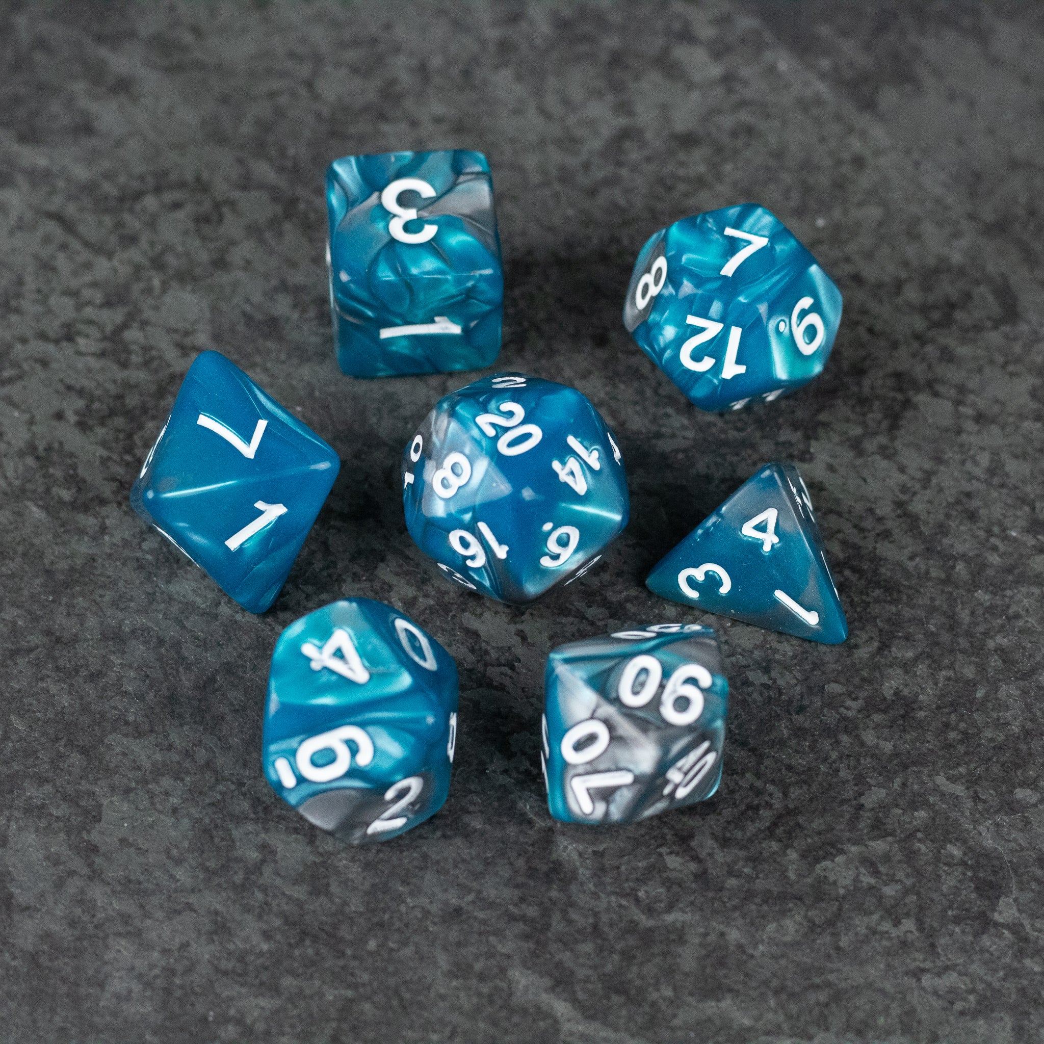 Blue and Gray Marbled Dice - Set of seven blue and gray marbled acrylic dice with white numbers on a gray textured background.