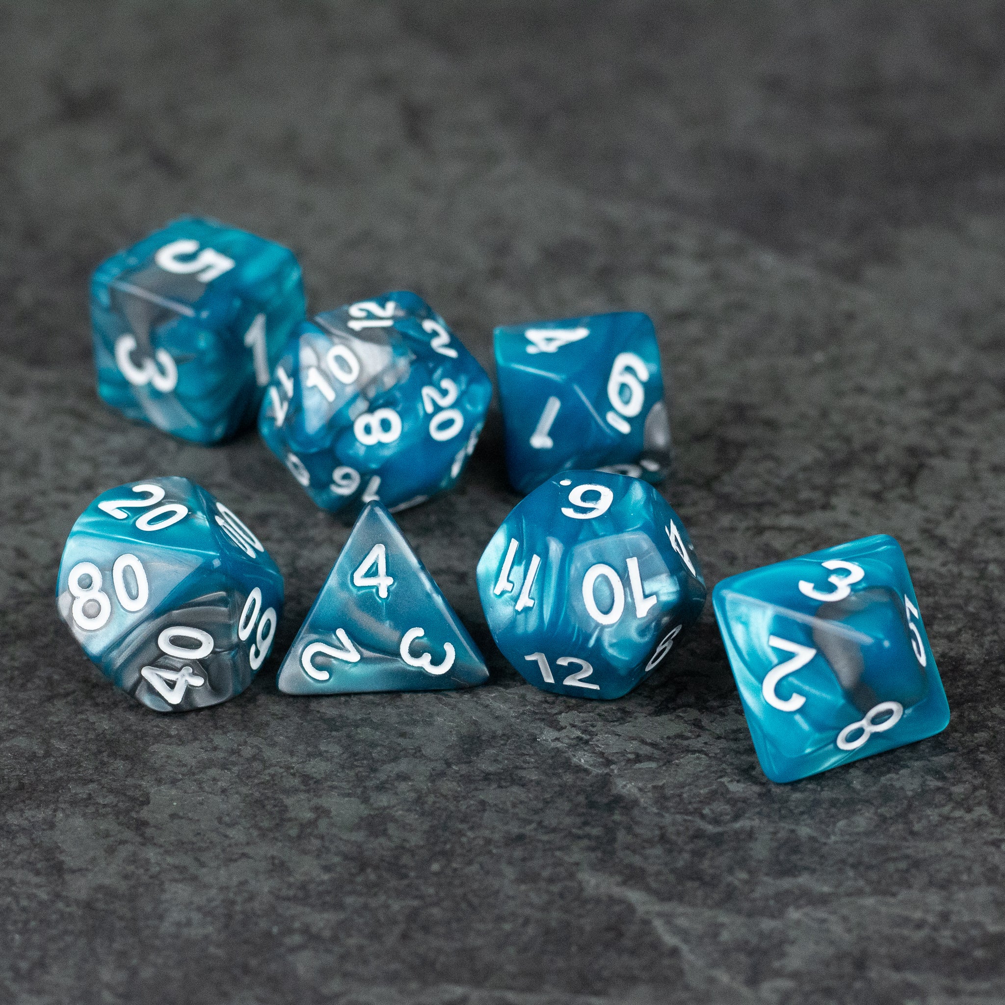 Blue and Gray Marbled Dice - Set of seven translucent blue and gray marbled acrylic dice with white numbers, including d20, d12, d10, d8, d6, and d4.