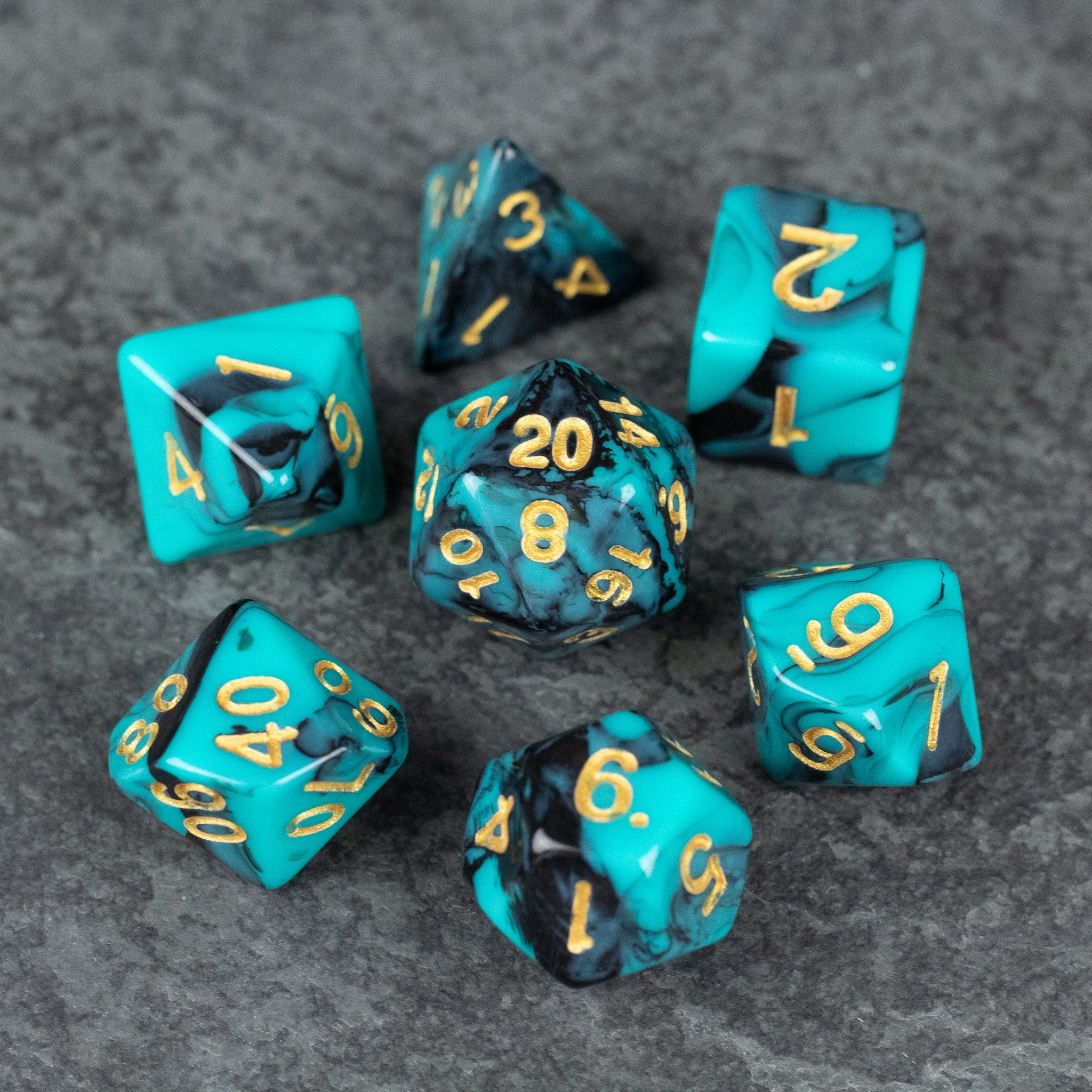 Mint and Black Marbled Dice Set - Set of seven acrylic dice with mint and black marbled pattern and gold numbers on gray surface.