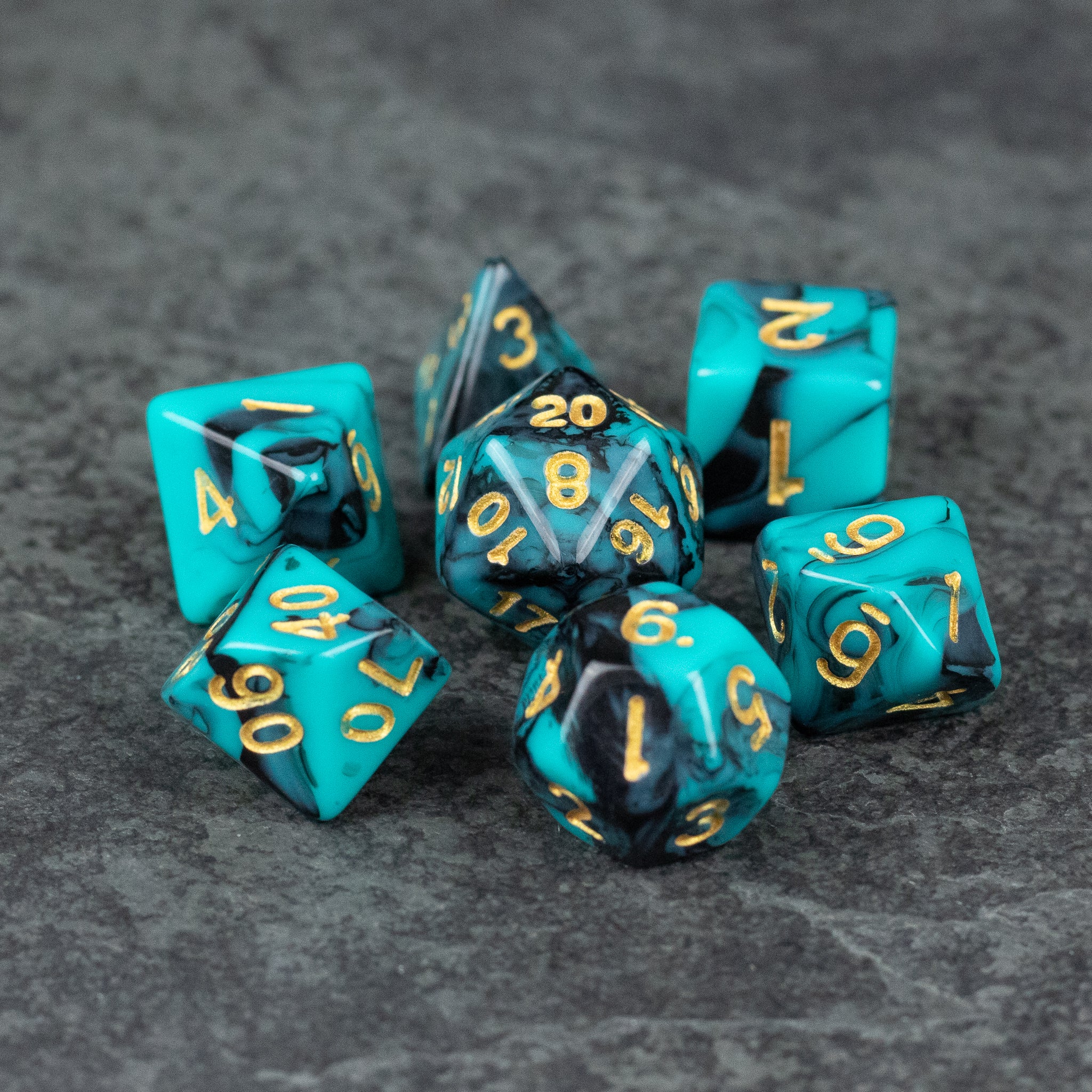 Mint and Black Marbled Dice Set - Set of seven acrylic dice with mint and black marbled patterns and gold numbers on a gray textured surface.