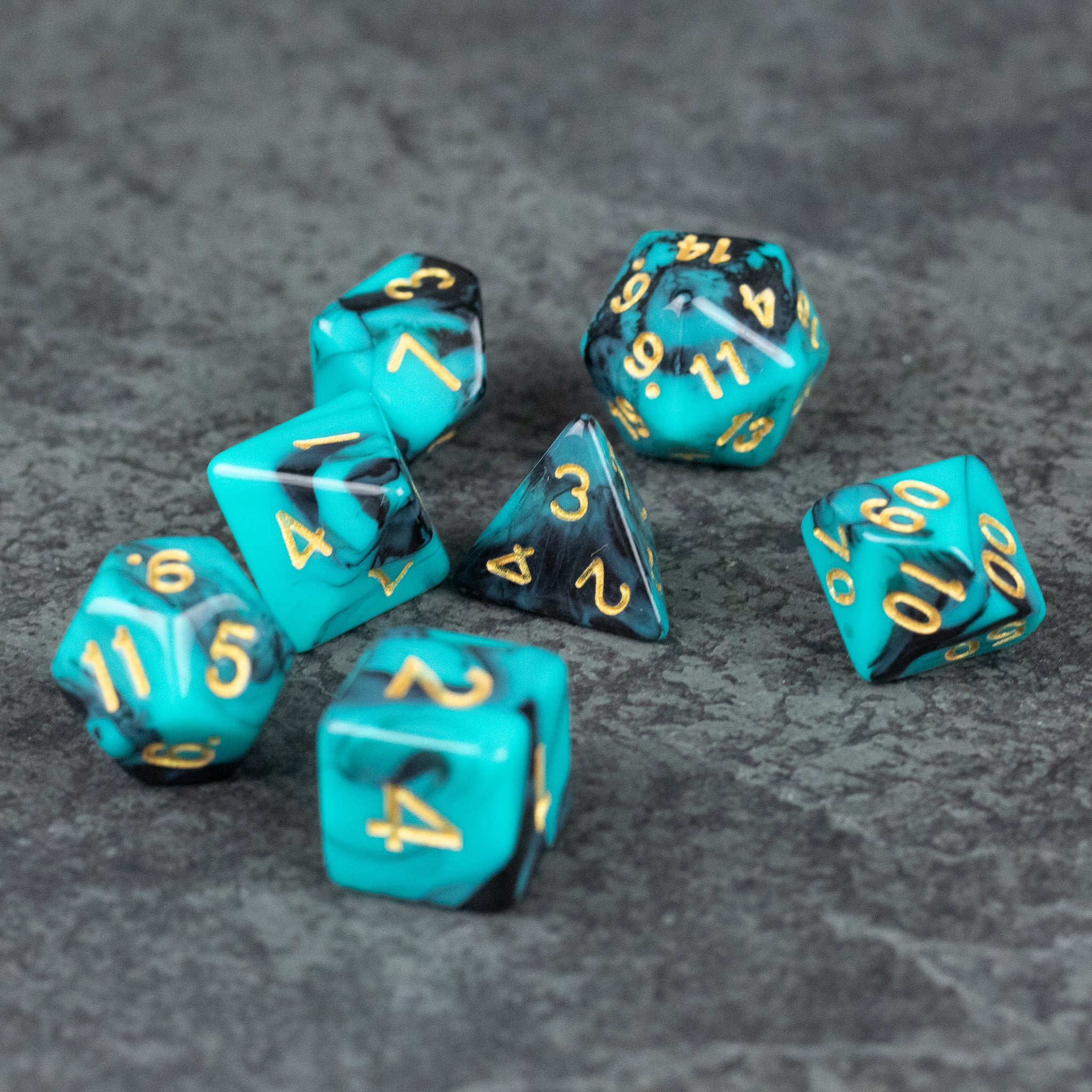 Mint and Black Marbled Dice Set - Set of seven mint and black marbled acrylic polyhedral dice with gold numbers on gray textured surface.