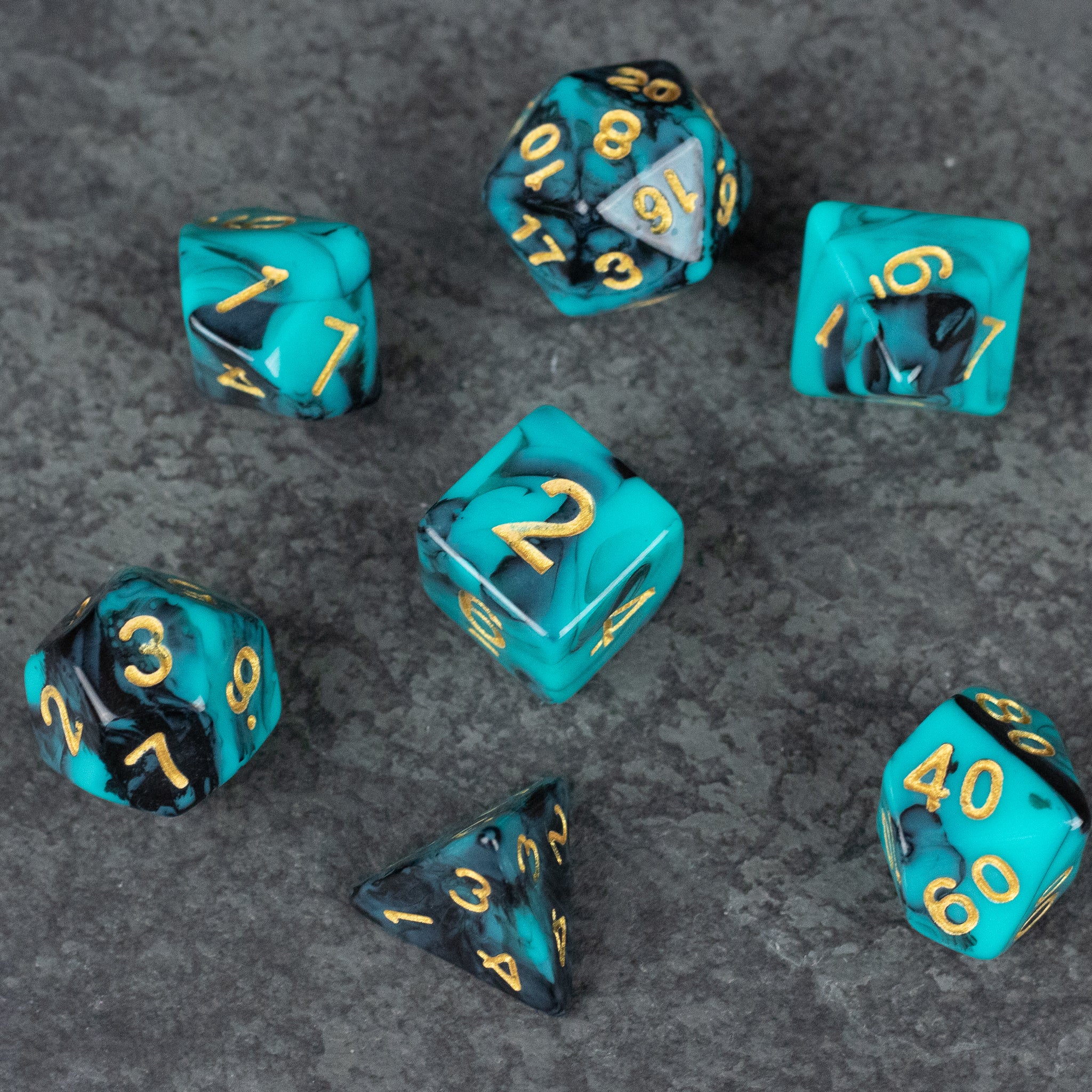 Mint and Black Marbled Dice Set - Seven-piece mint and black marbled acrylic dice set with gold numbering on a gray surface.