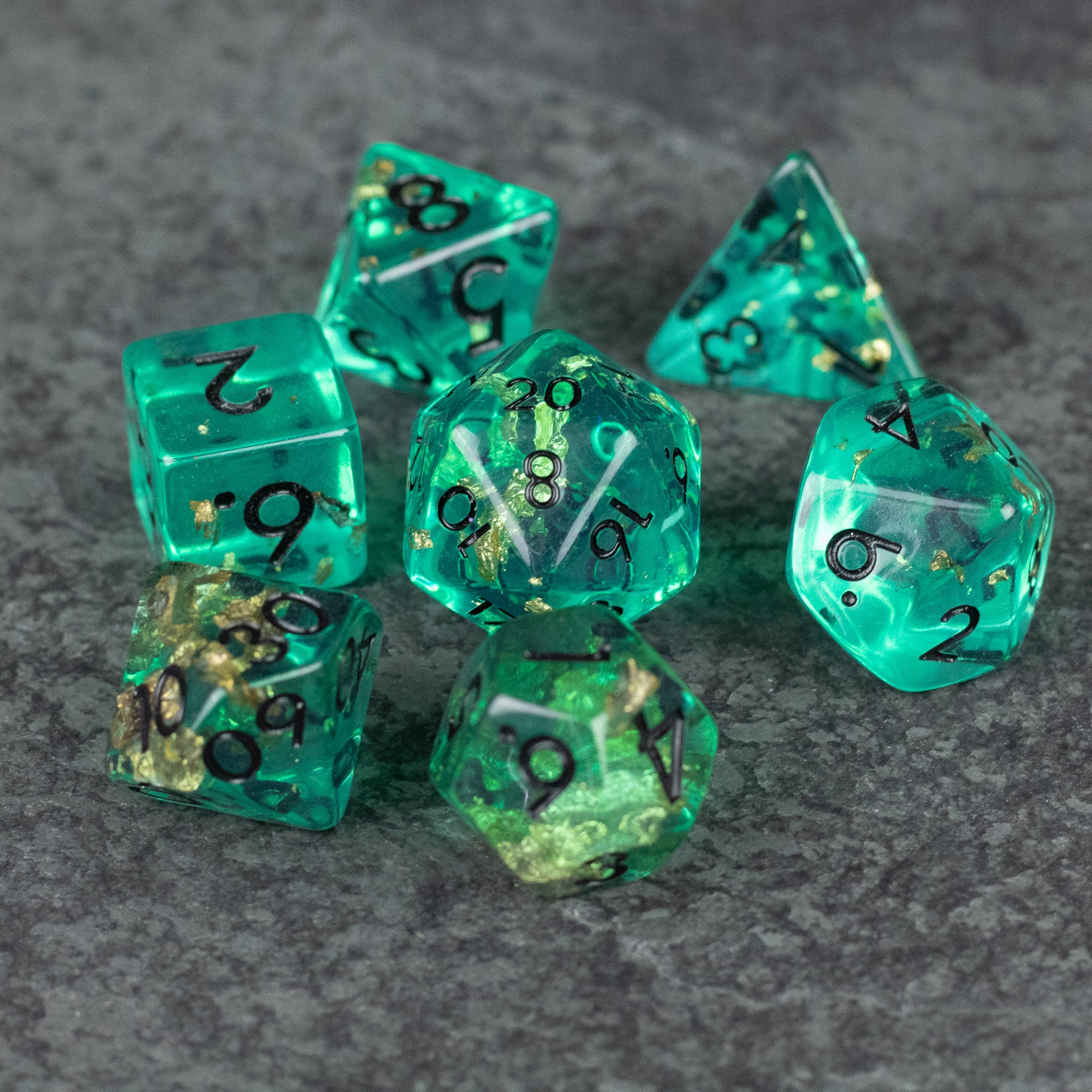 Teal Foil Dice Set - Teal translucent foil dice set with black numbers, including d4, d6, d8, d10, d12, and d20 on gray background.