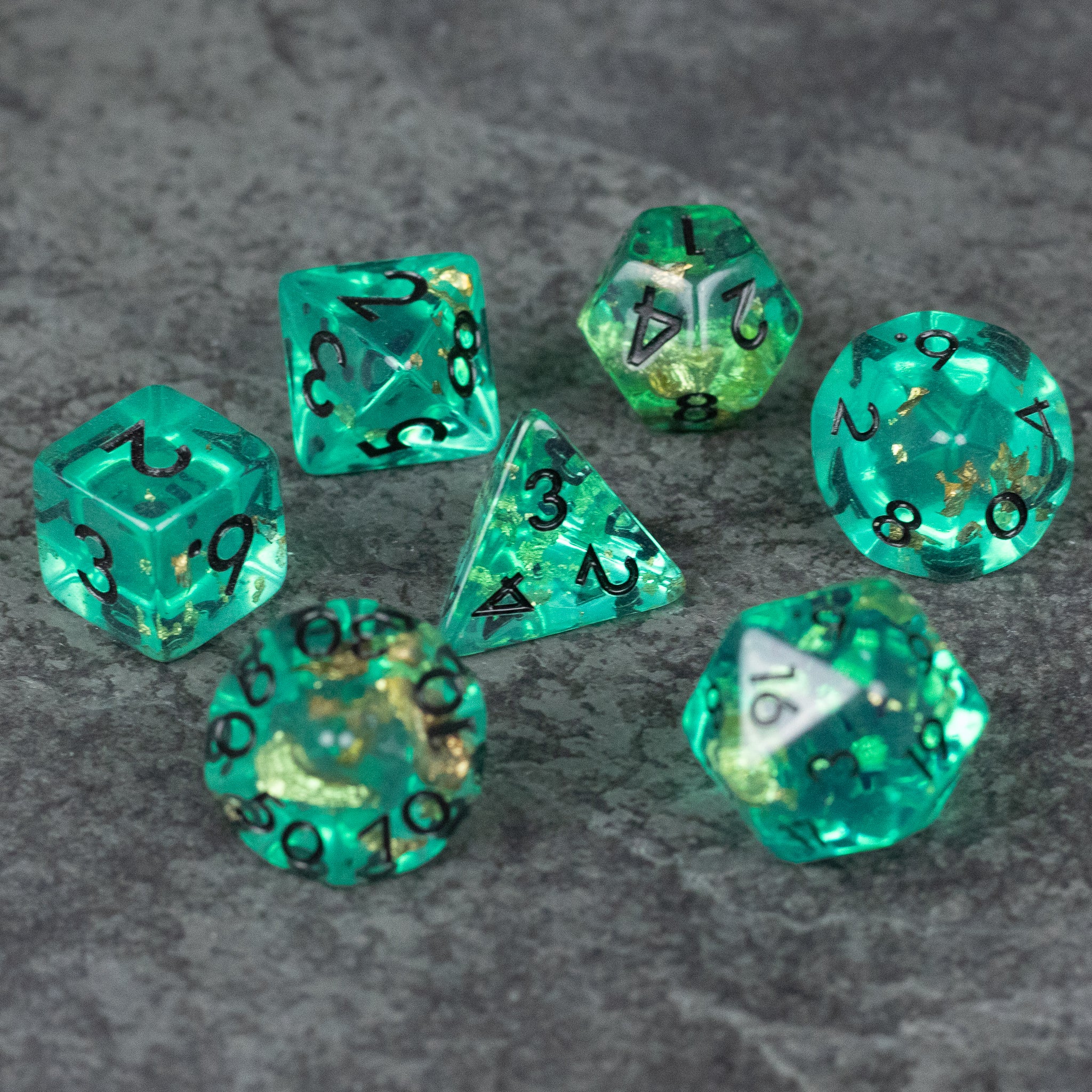 Teal Foil Dice Set - Set of seven teal foil polyhedral dice with black numbering on gray surface.