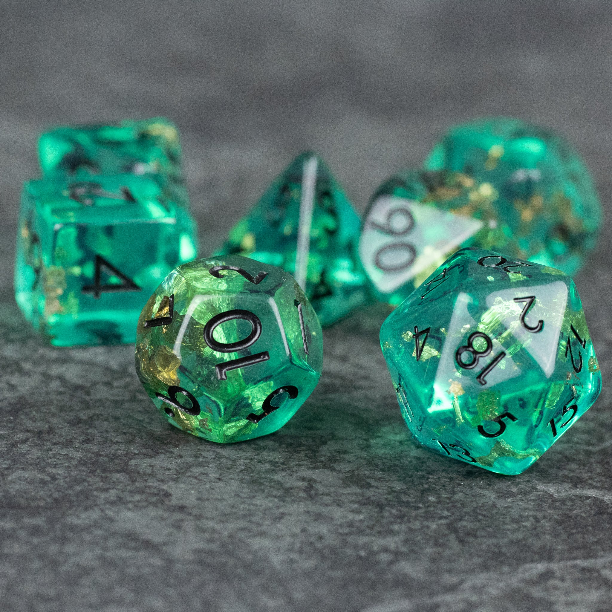 Teal Foil Dice Set - Set of teal translucent foil dice with black numbers, featuring multiple polygon shapes for tabletop games.