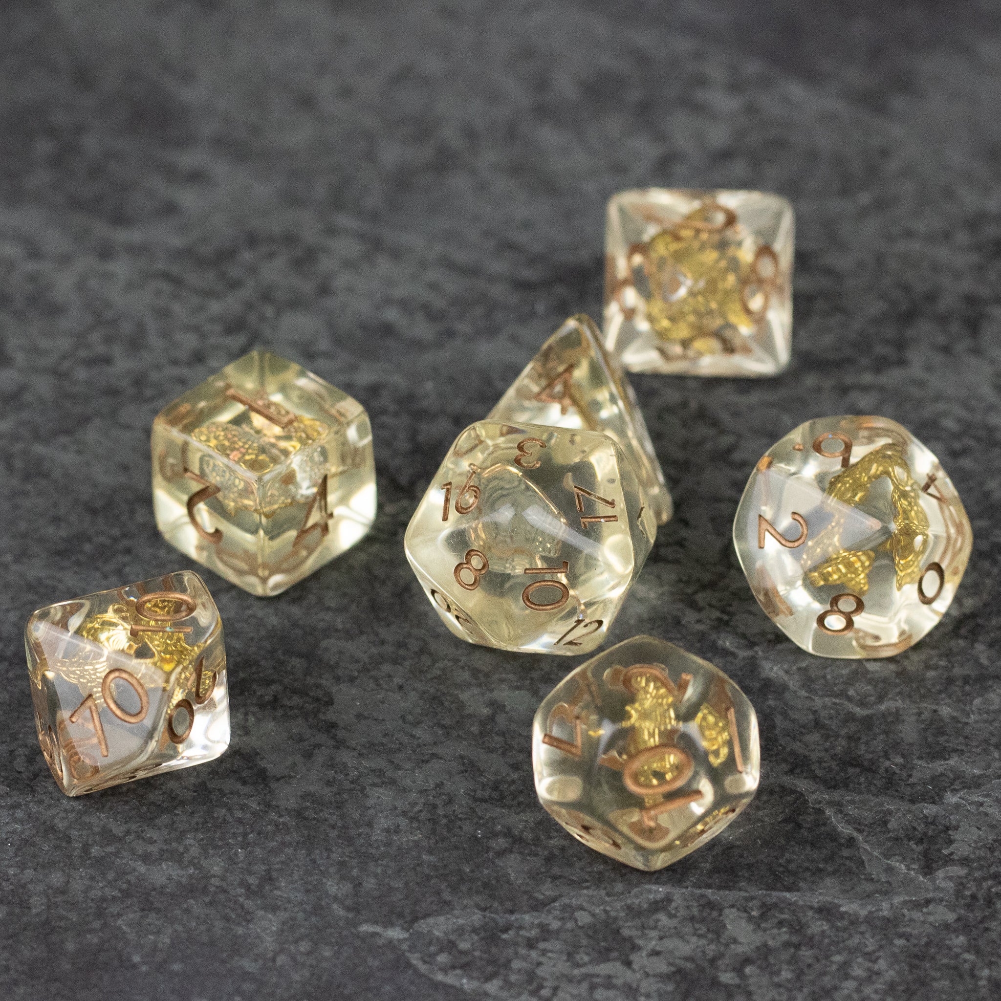 Gold Charm Butterfly Dice Set - Transparent polyhedral dice set with embedded gold butterfly charms on gray surface.