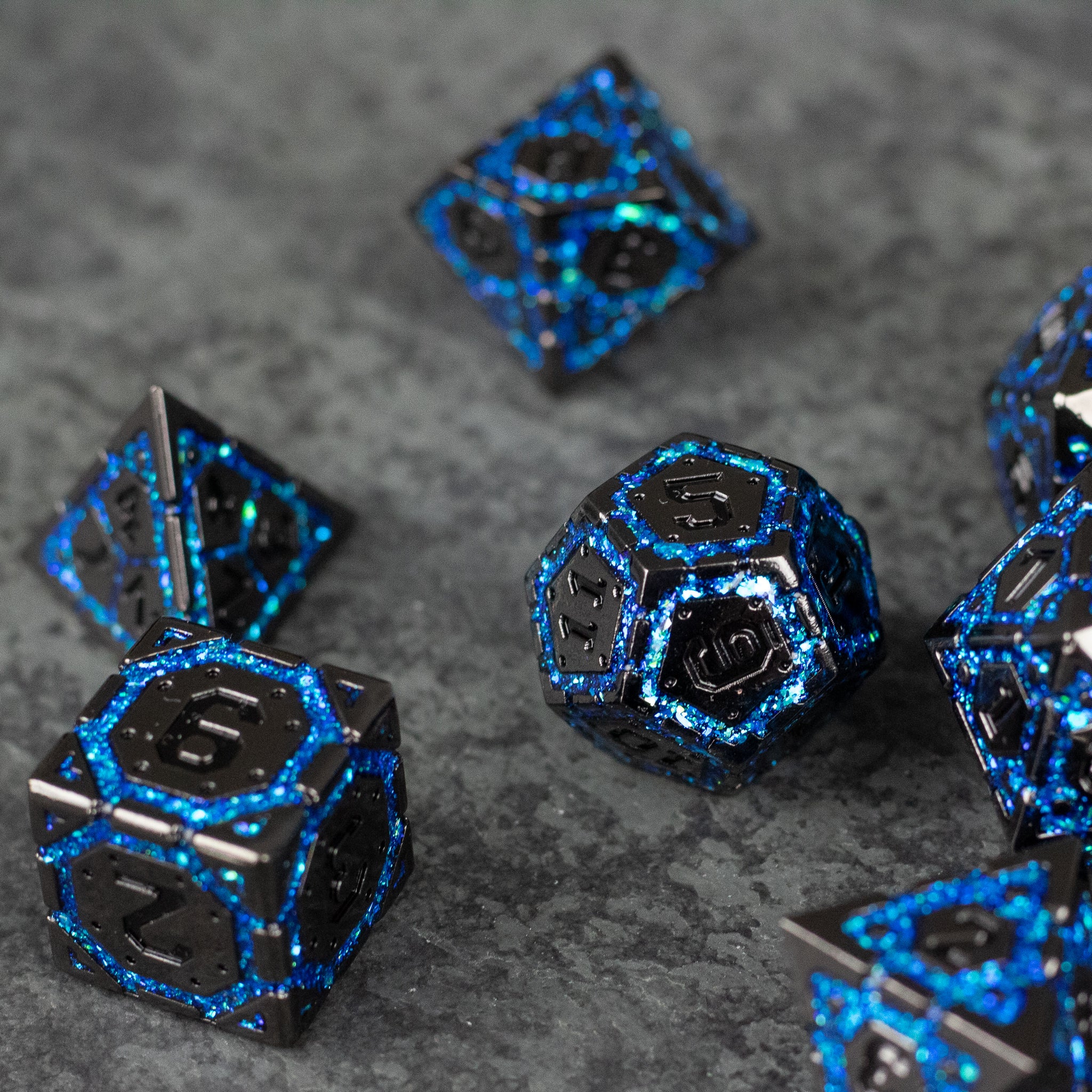 Blue Arcane Ward - Black metal polyhedral dice with shimmering blue arcane designs on a gray textured surface.