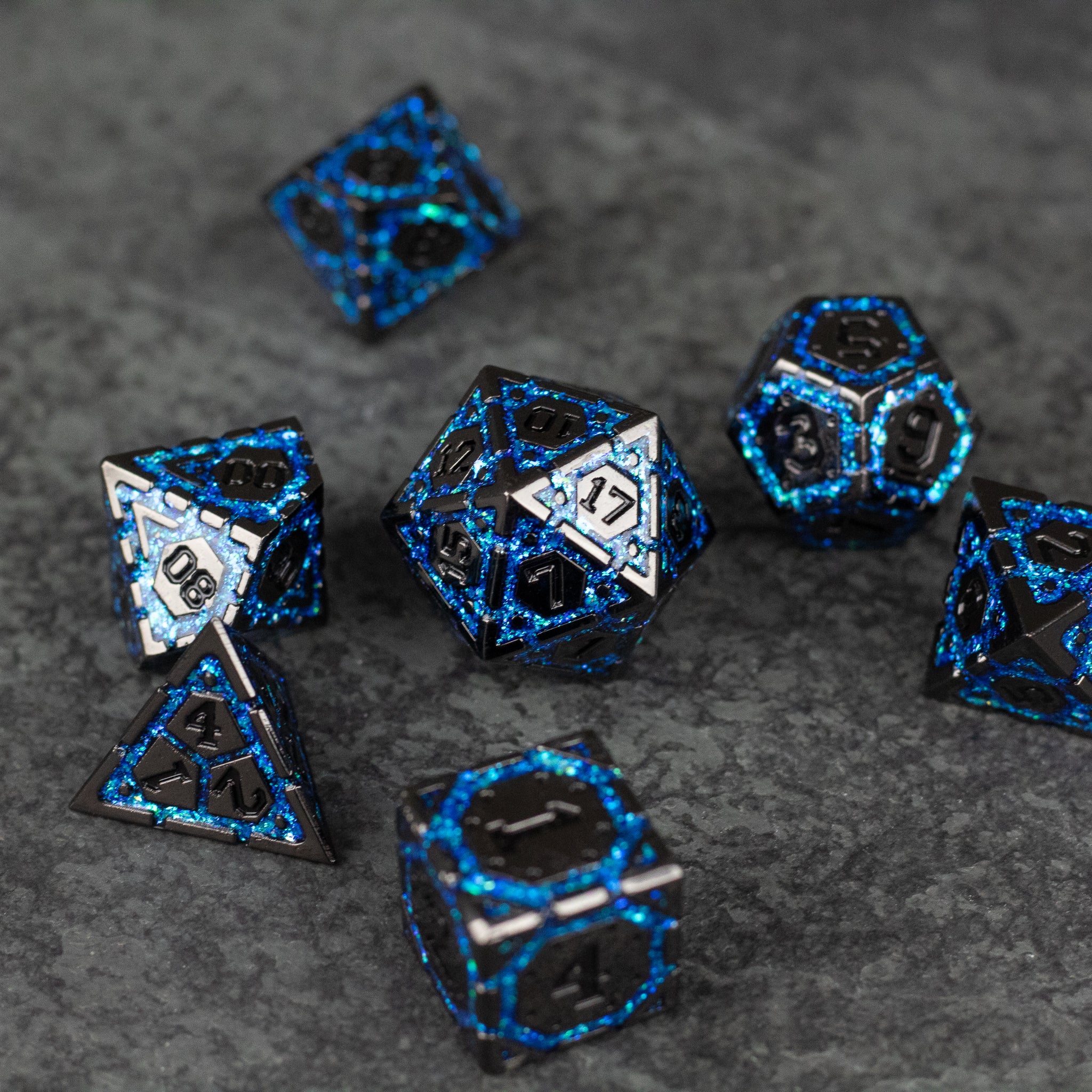 Blue Arcane Ward - Set of black metal polyhedral dice with glowing blue arcane pattern and white number inlays on textured dark surface.